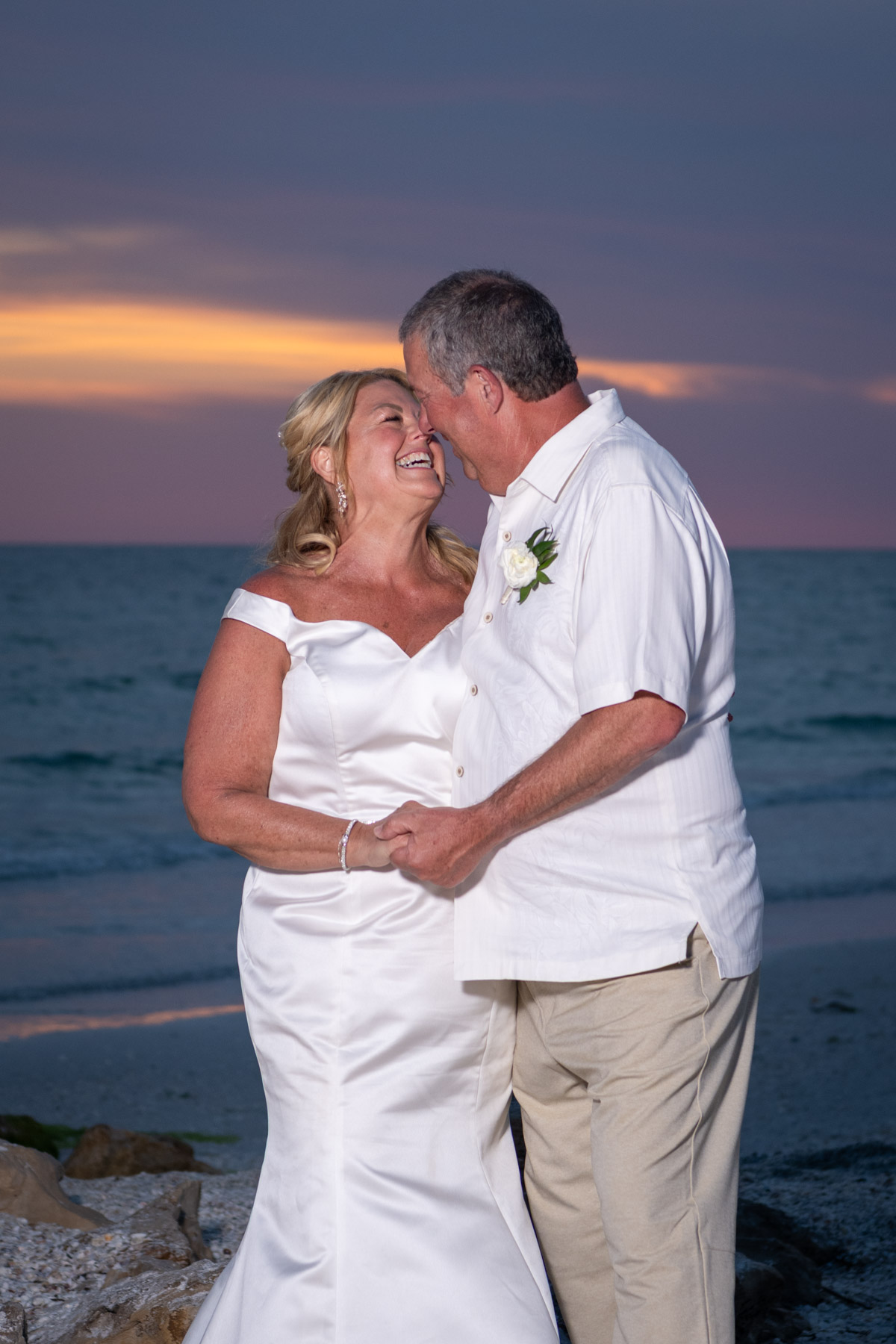 bride and groom look at each other as the sun sets behind them