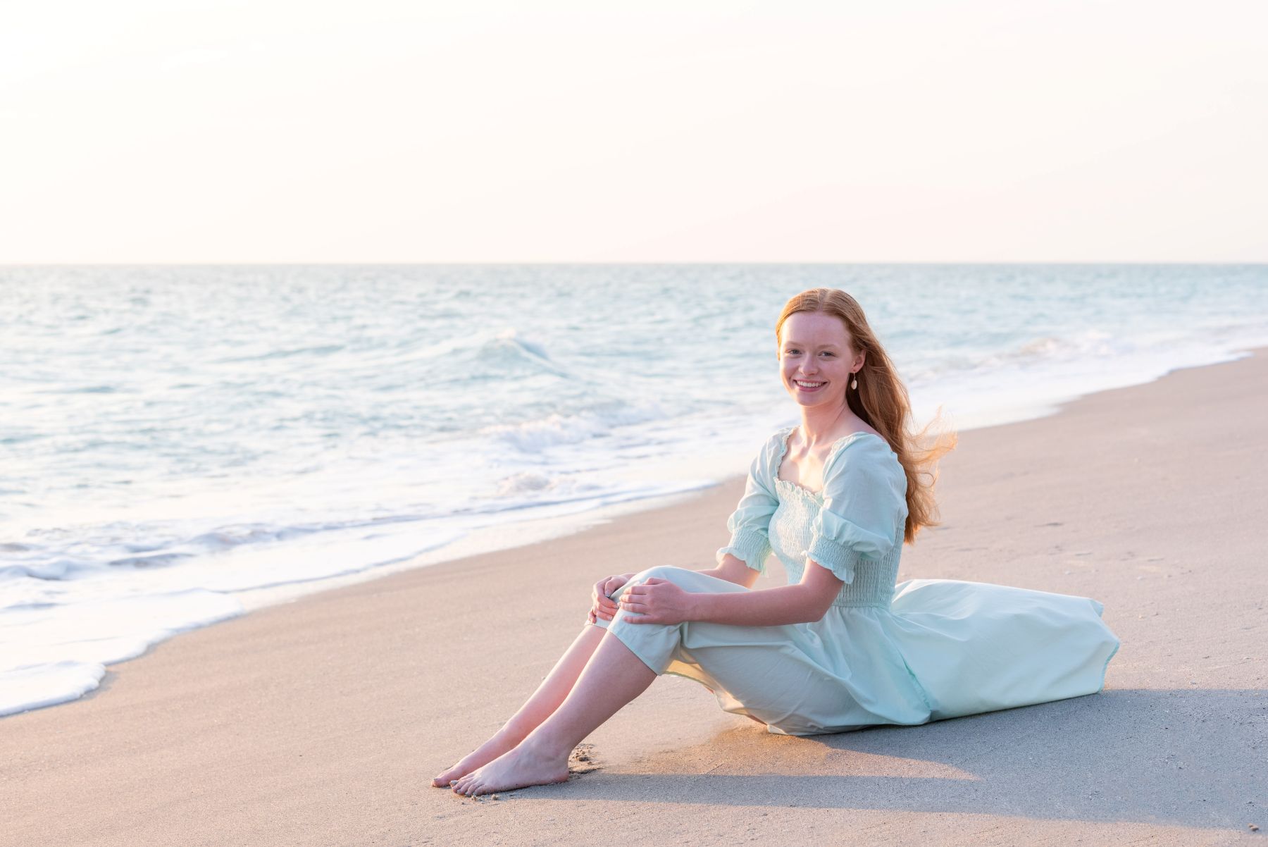 girl sitting on beach in aqua dress