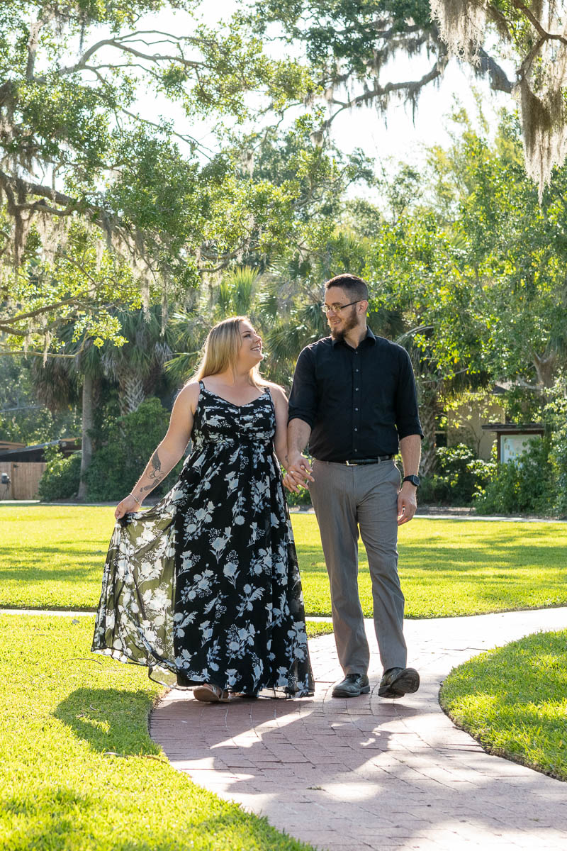 couple holds hands as they walk along the sidewalk