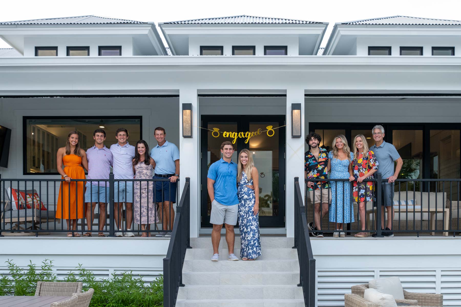family stands on front porch of their home to celebrate the engagement of their children on Boca Grande
