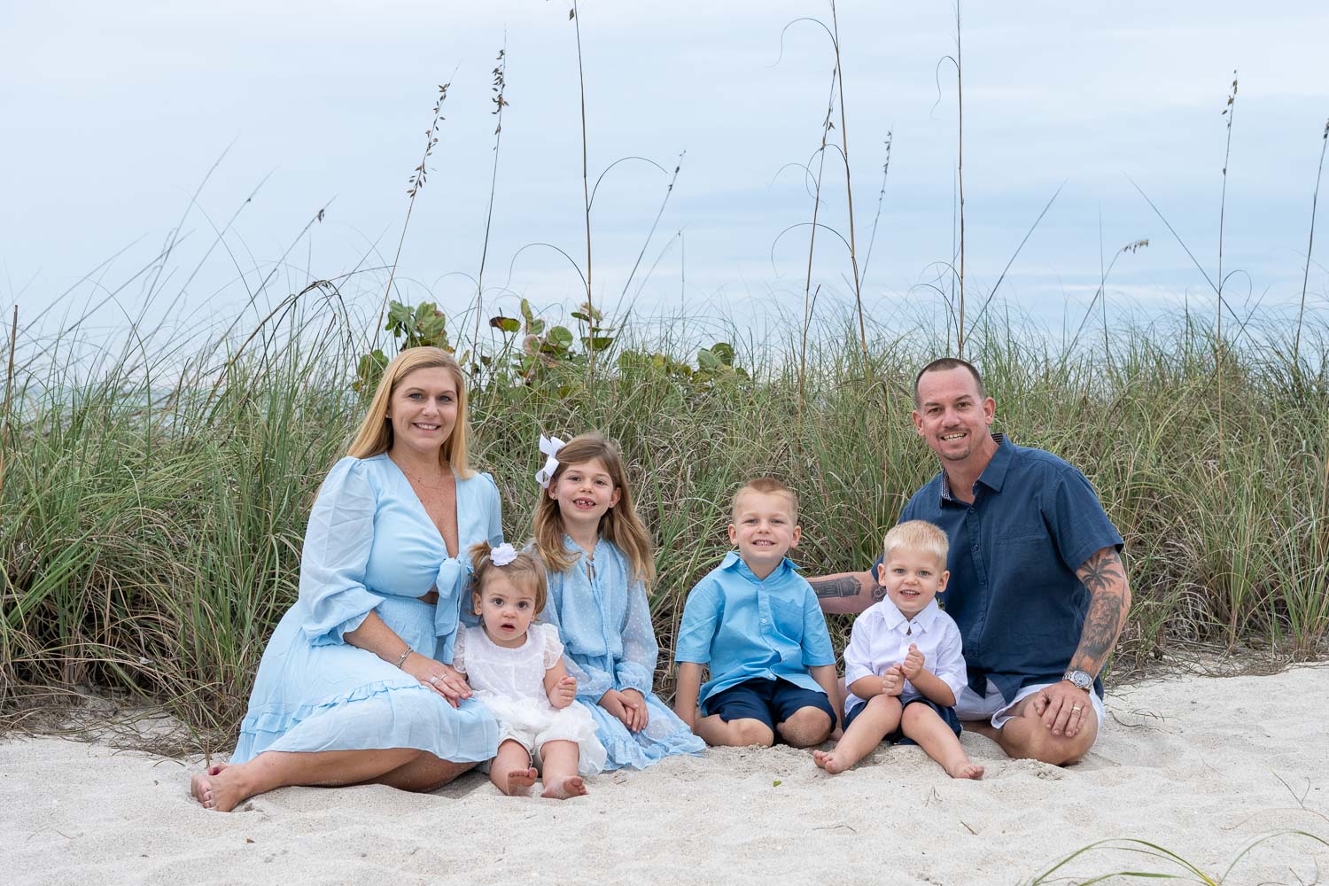 parents sitting with their four children on the beach