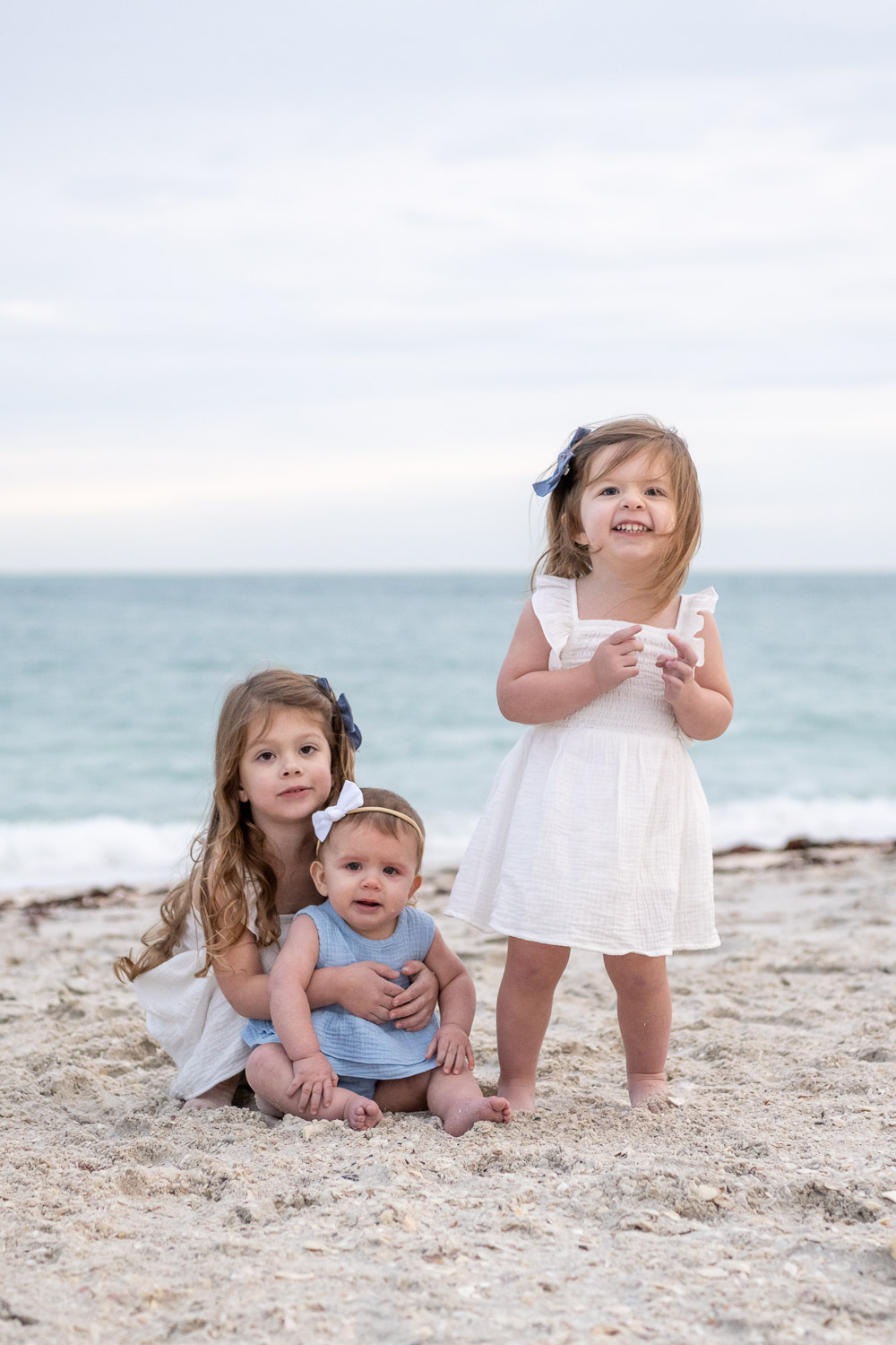 three little girls play in the sand on the beach