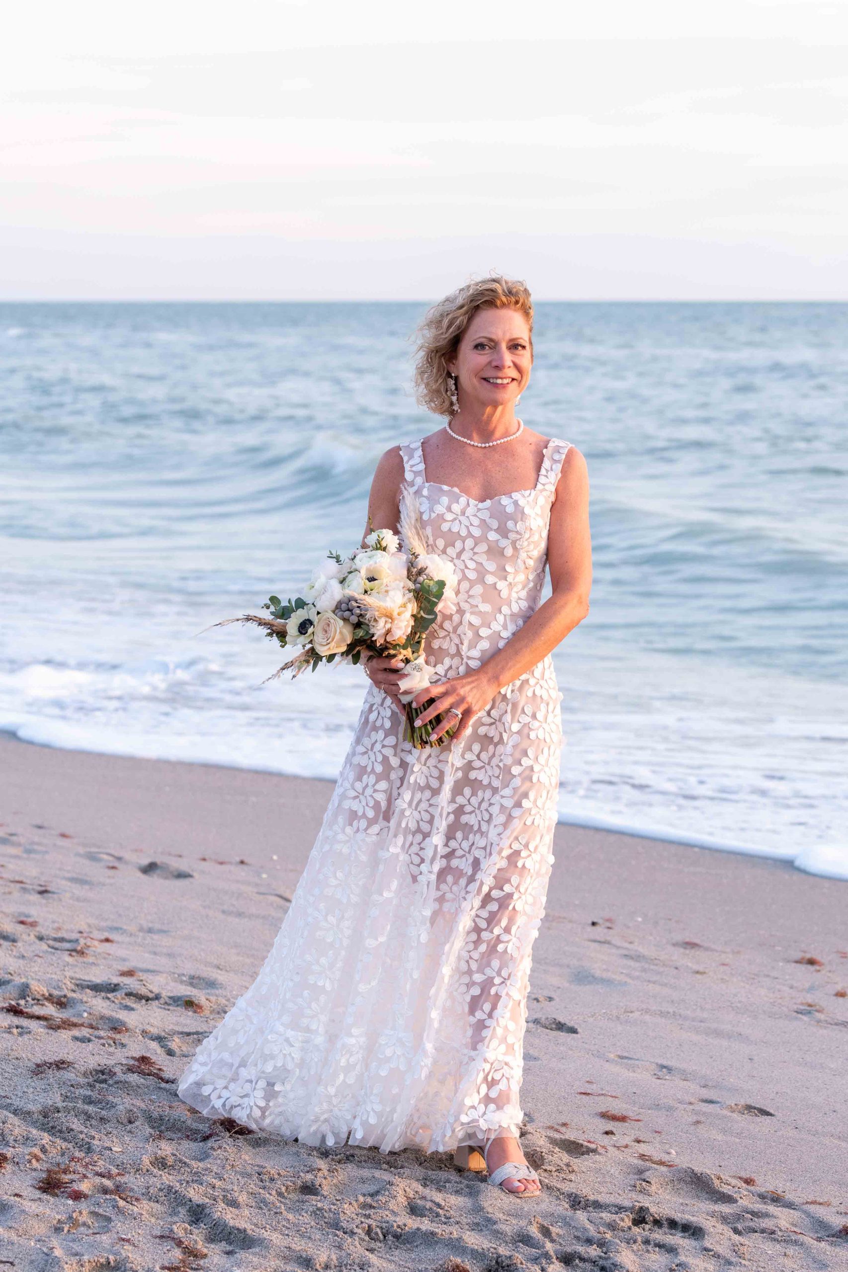 bride on the beach with her bridal bouquet at sunset