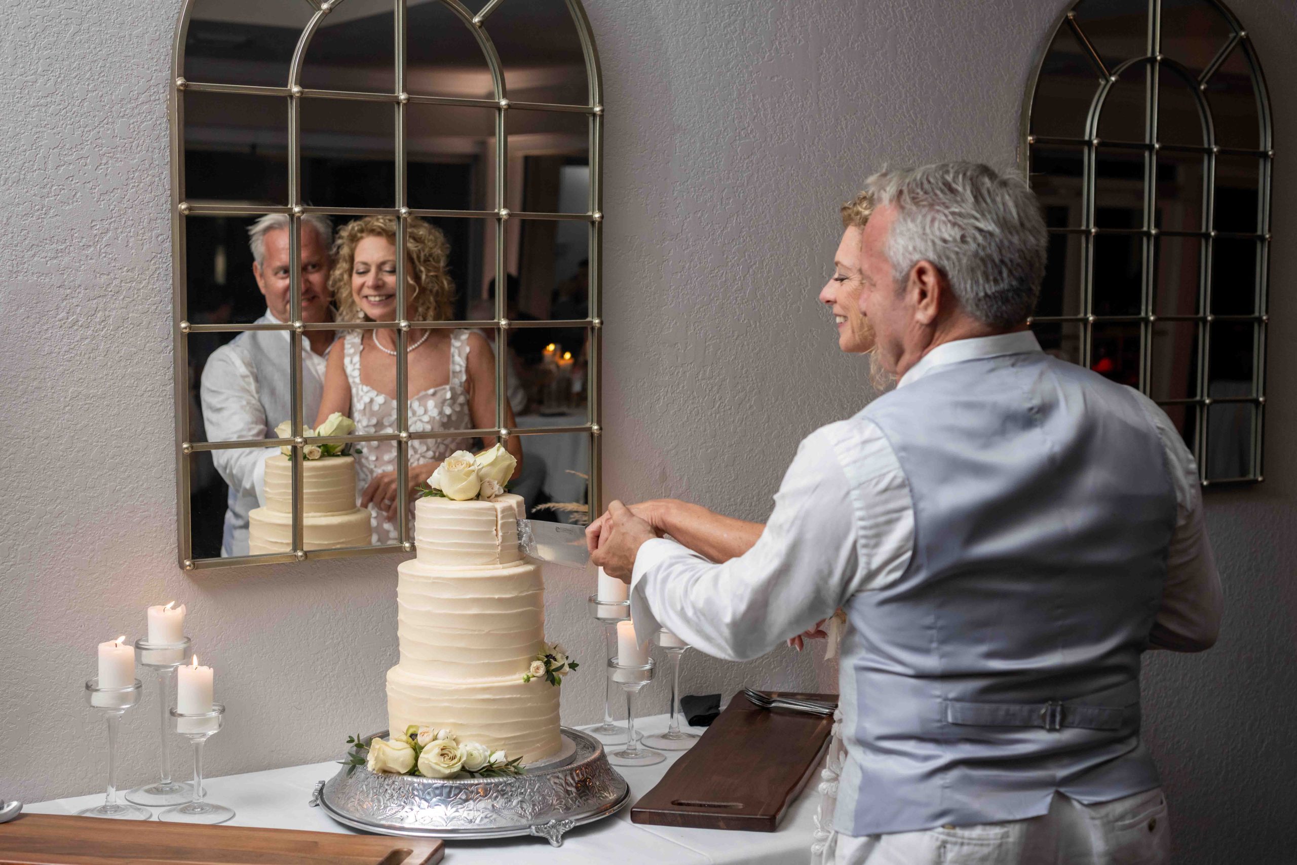 reflection in mirror as bride and groom cut their wedding cake
