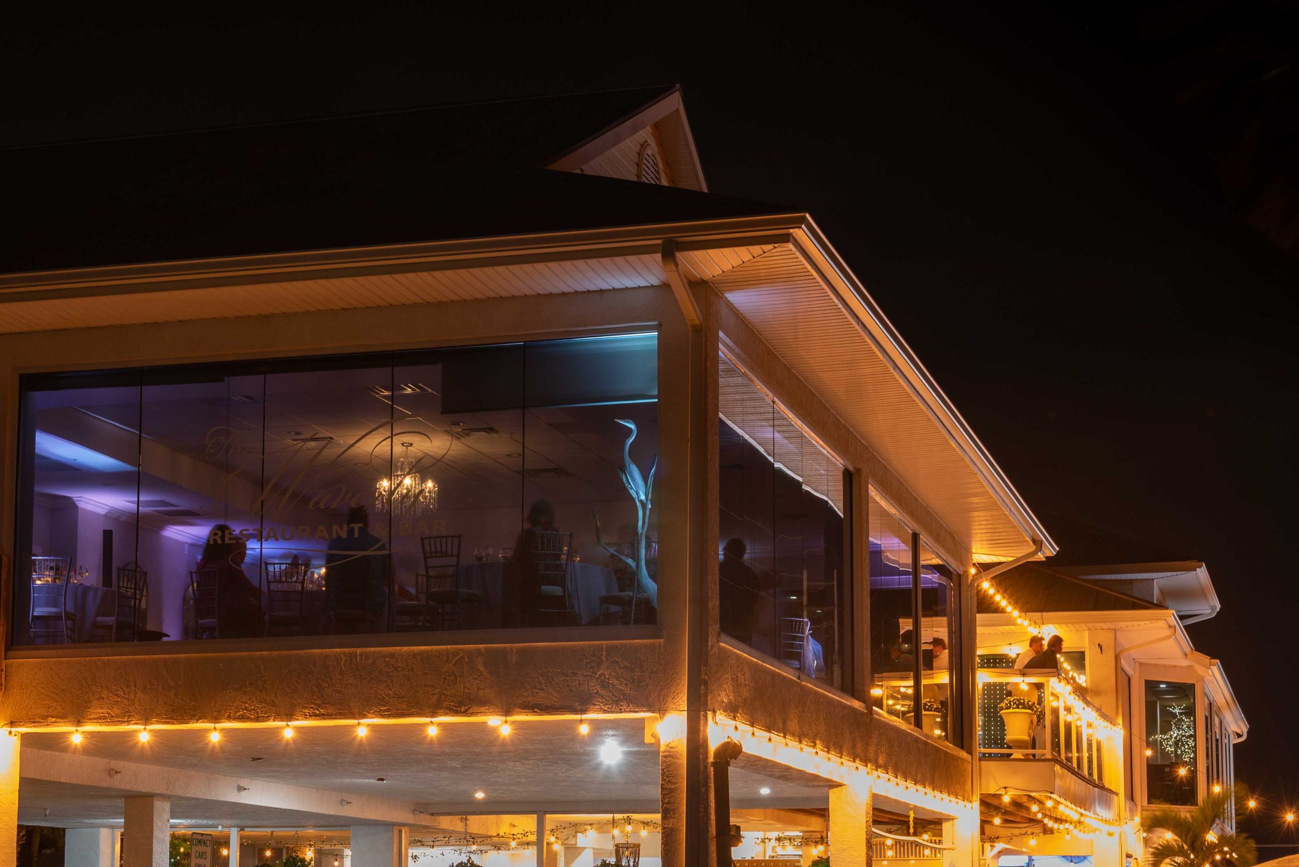 exterior night photo of The Waverly on Manasota Key looking into the windows at the wedding reception