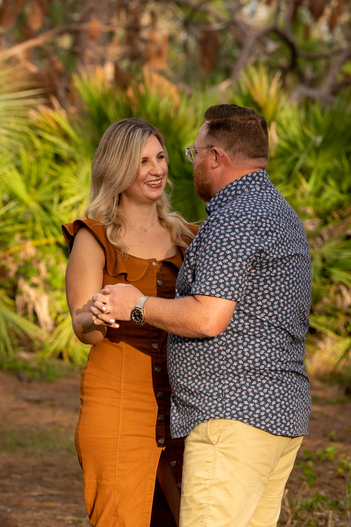 woman smiles at her fiance as they hold each other close in a park