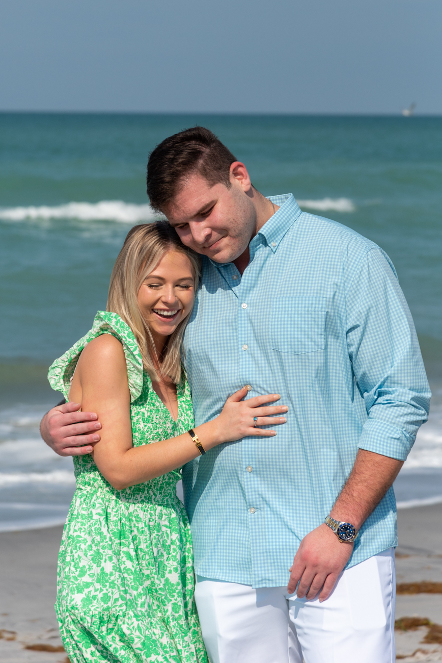 newly engaged couple hold each other close and smile