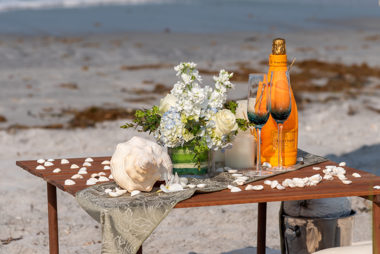 conch shell, flowers and champagne set up on a small table