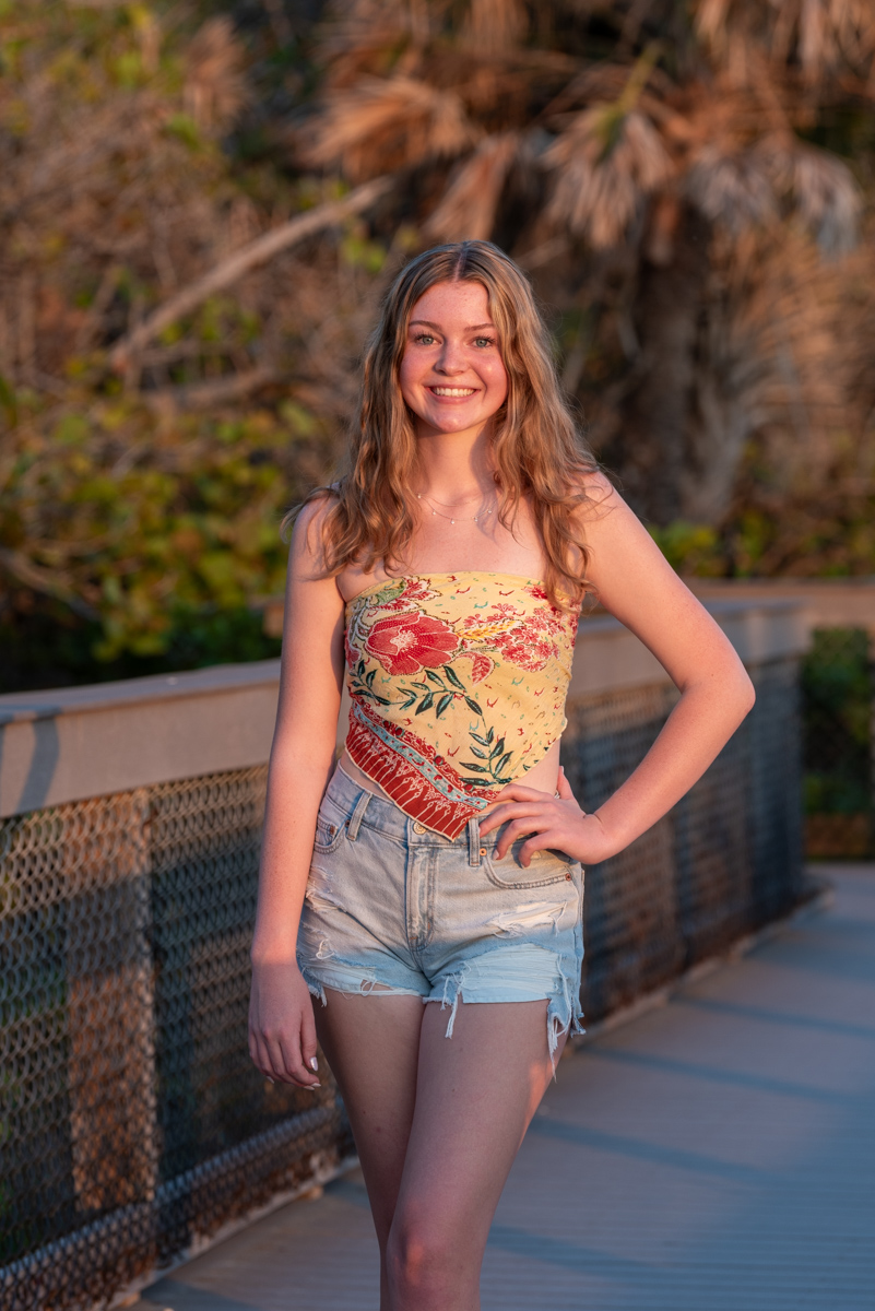 senior girl on boardwalk with sun glowing on face