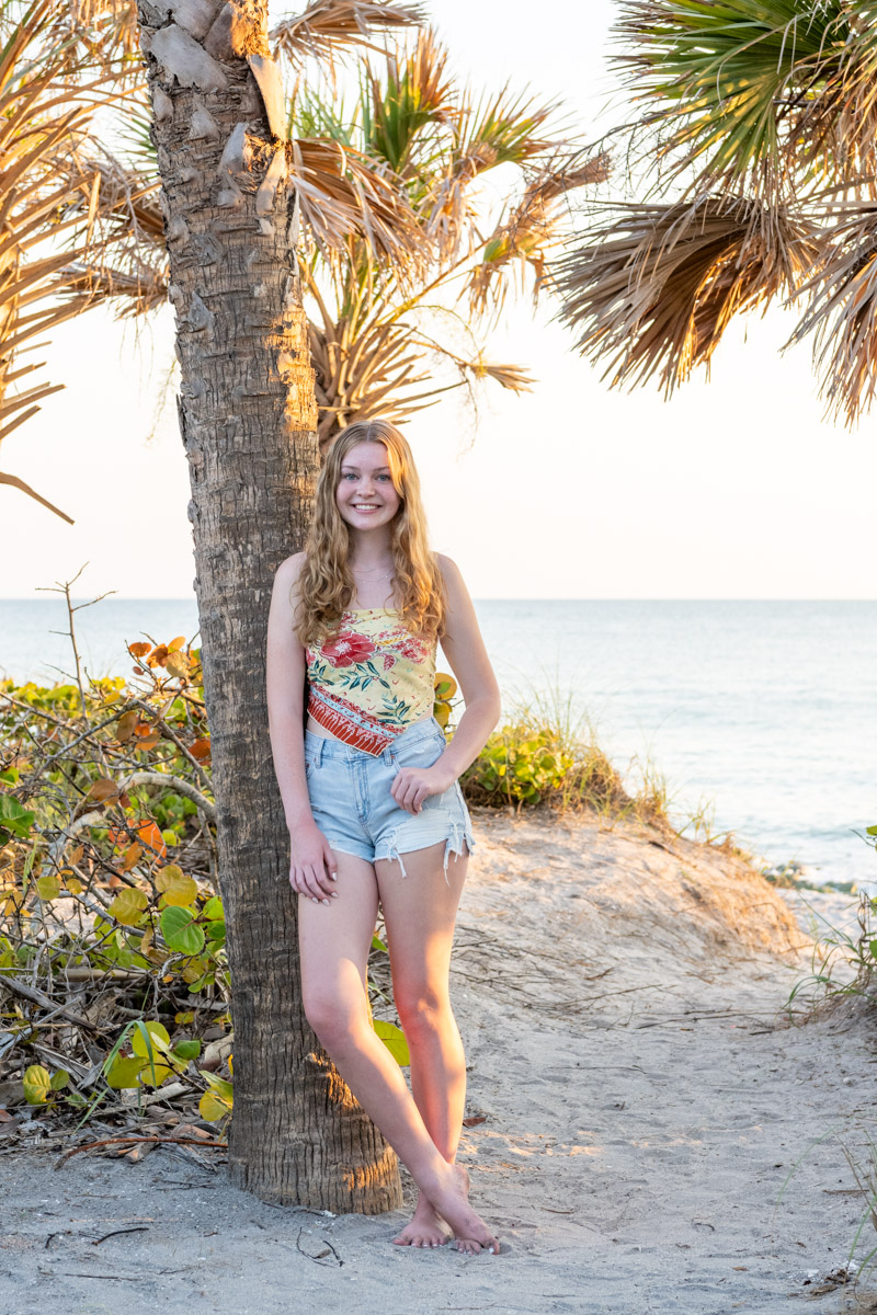 senior girl leaning against palm tree