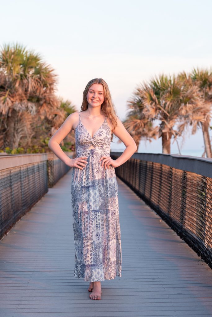 girl in purple dress on boardwalk at Caspersen Beach with palm trees on side