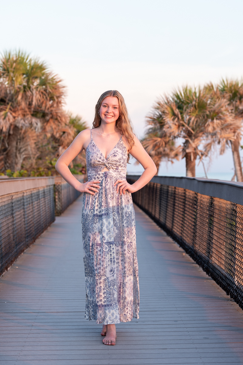 girl in purple dress on boardwalk at Caspersen Beach with palm trees on side