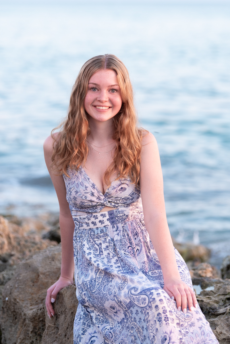 senior session at Caspersen Beach with girl sitting on rocks with water in the background