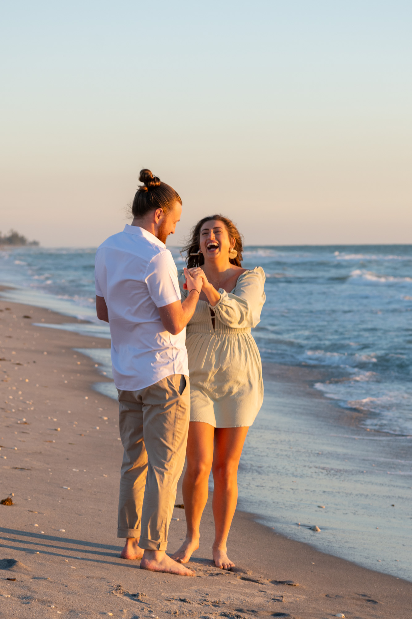 they both look at her new engagement ring in excitement as the waves gently roll in