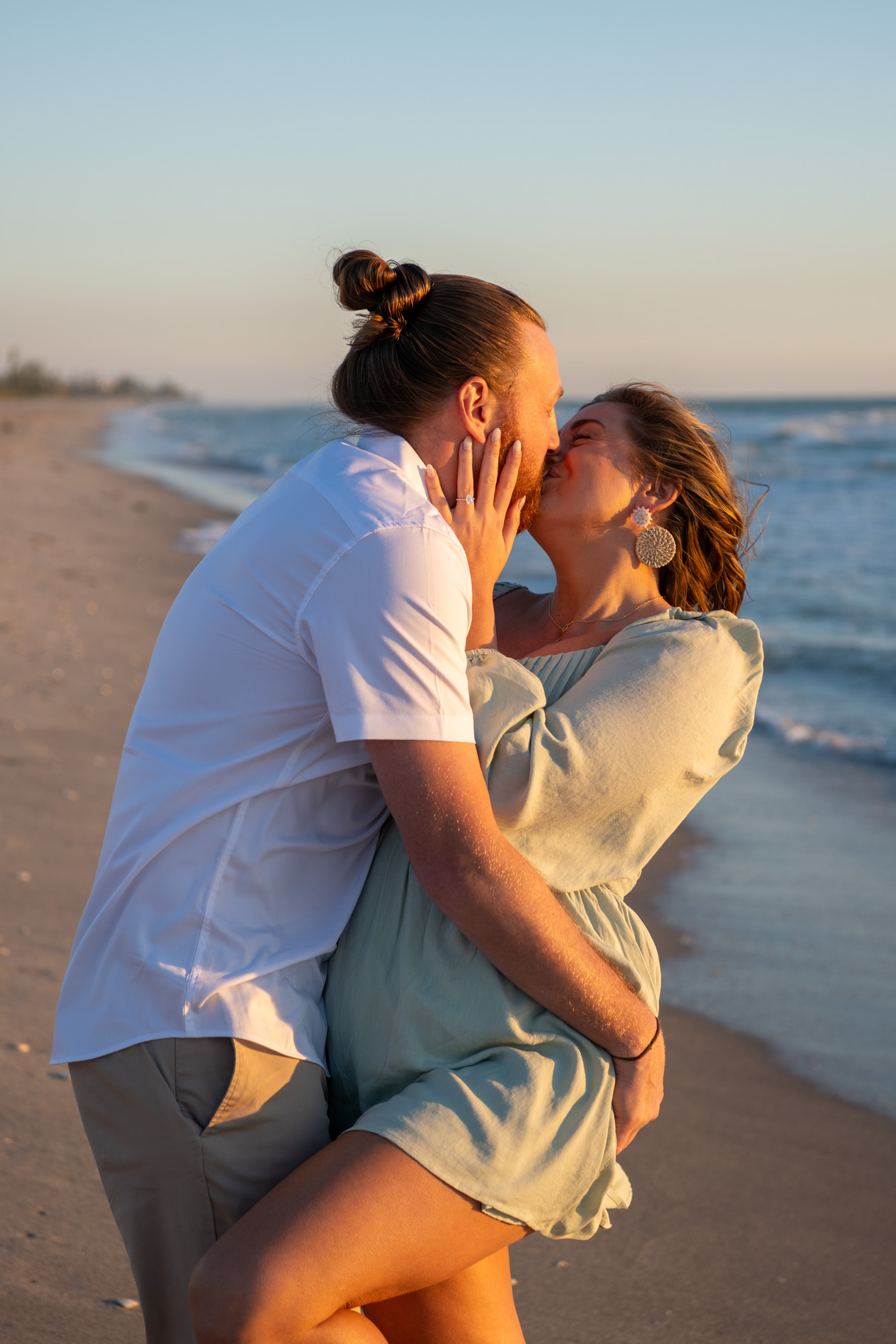guy starts to tip back girlfriend as they kiss after their surprise engagement on Englewood Beach