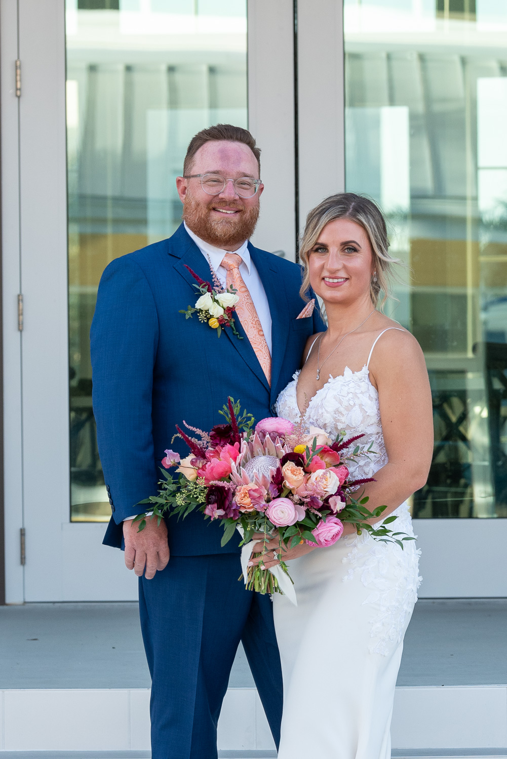 bride holds her bouquet as she stands by her husband on the steps of Solis Hall