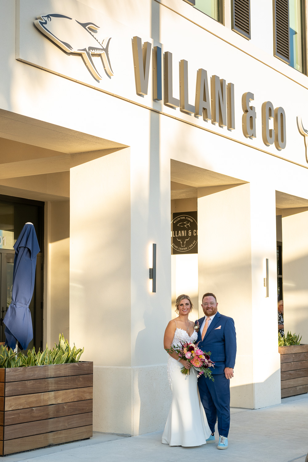 bride and groom stand in front of Villani & Co before wedding reception