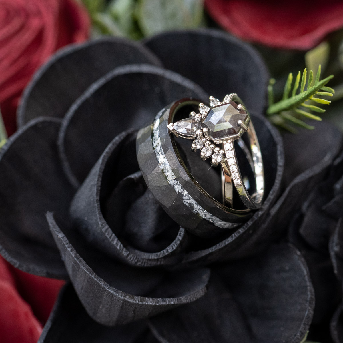 unique wedding bands placed on black wood flowers for her bridal bouquet