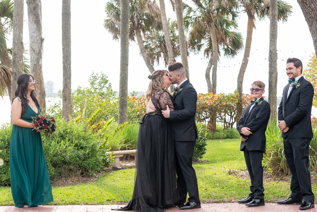 her son looks on the bride and groom kiss after wedding at Bay Preserve