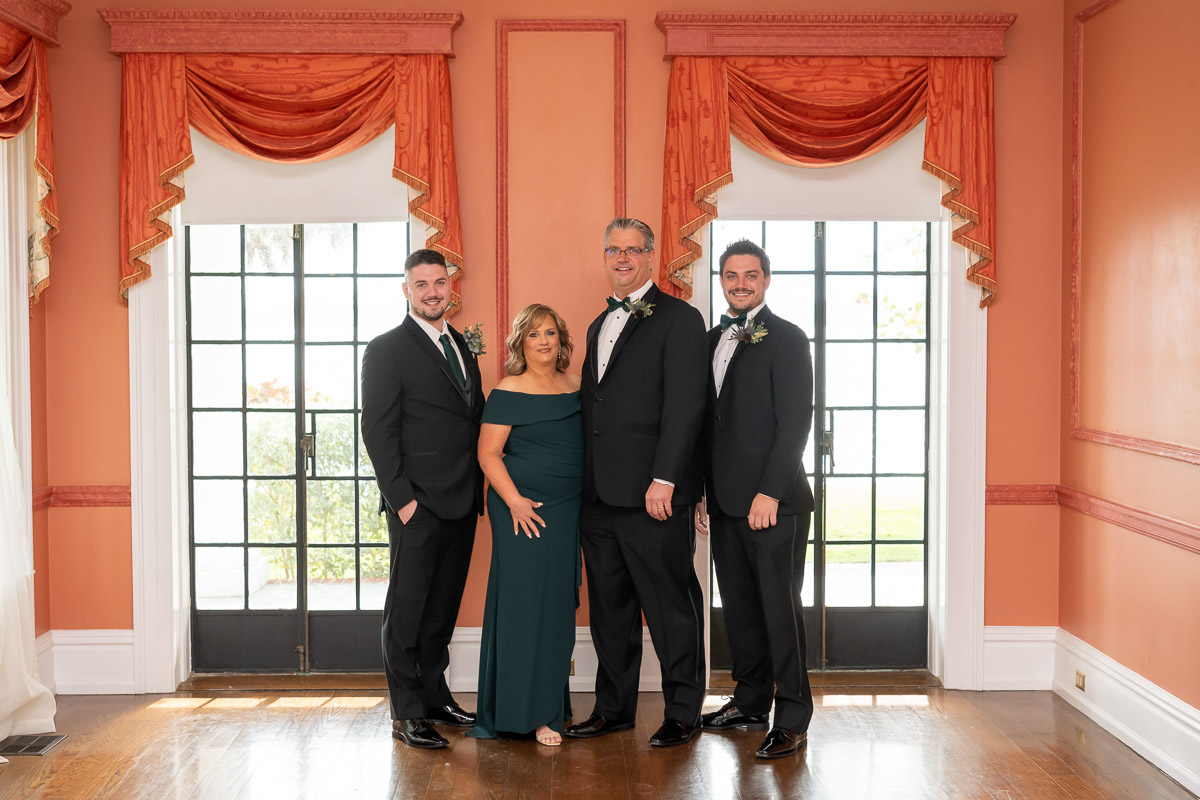 the groom's family stands for a family photo before the wedding