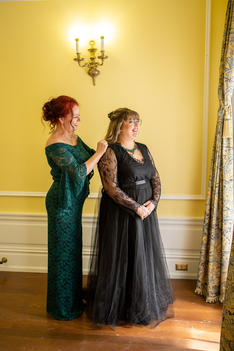 the bride's mother attaches her necklace in the getting ready room as the natural window light illuminates them