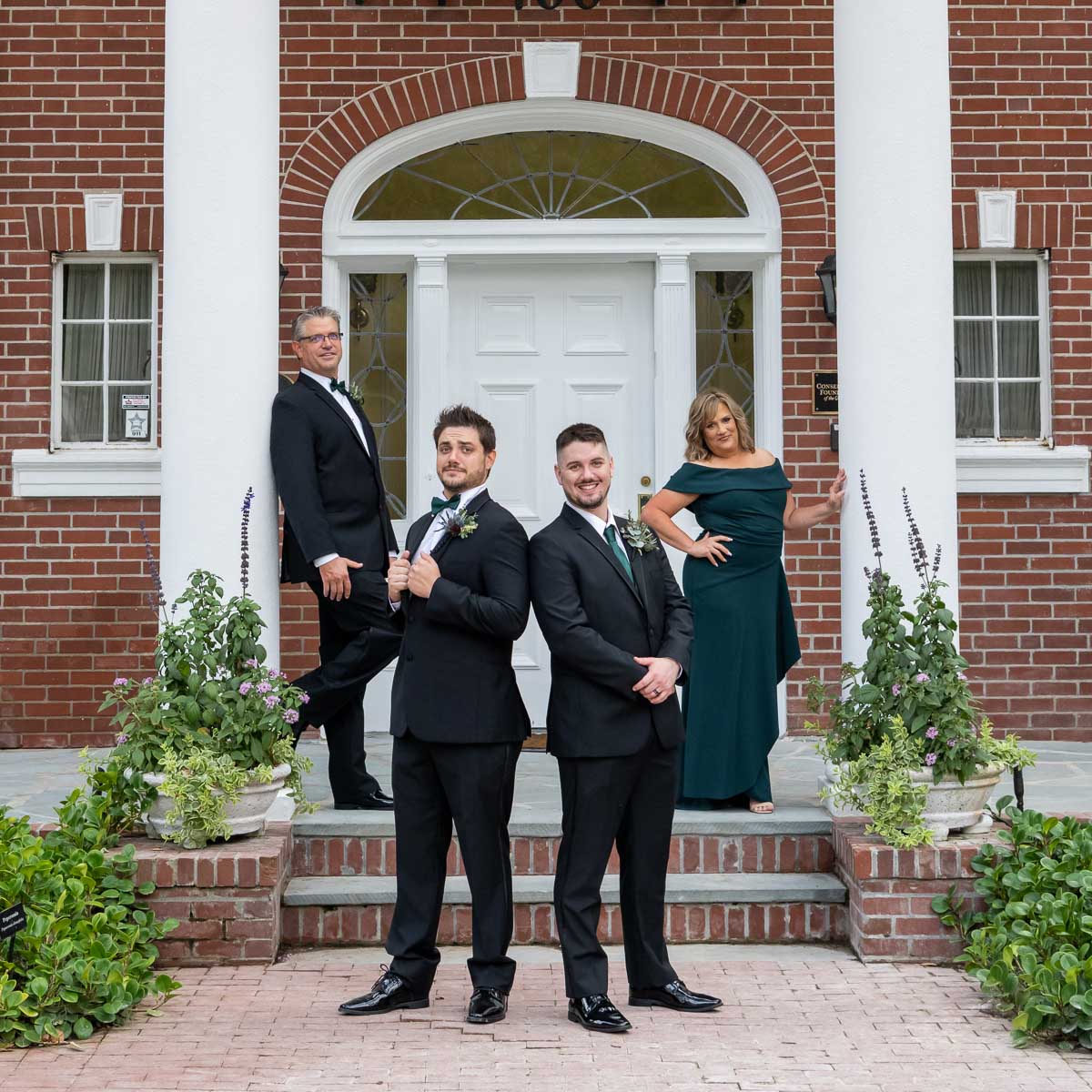 the groom's family poses on the steps of the mansion at Bay Preserve