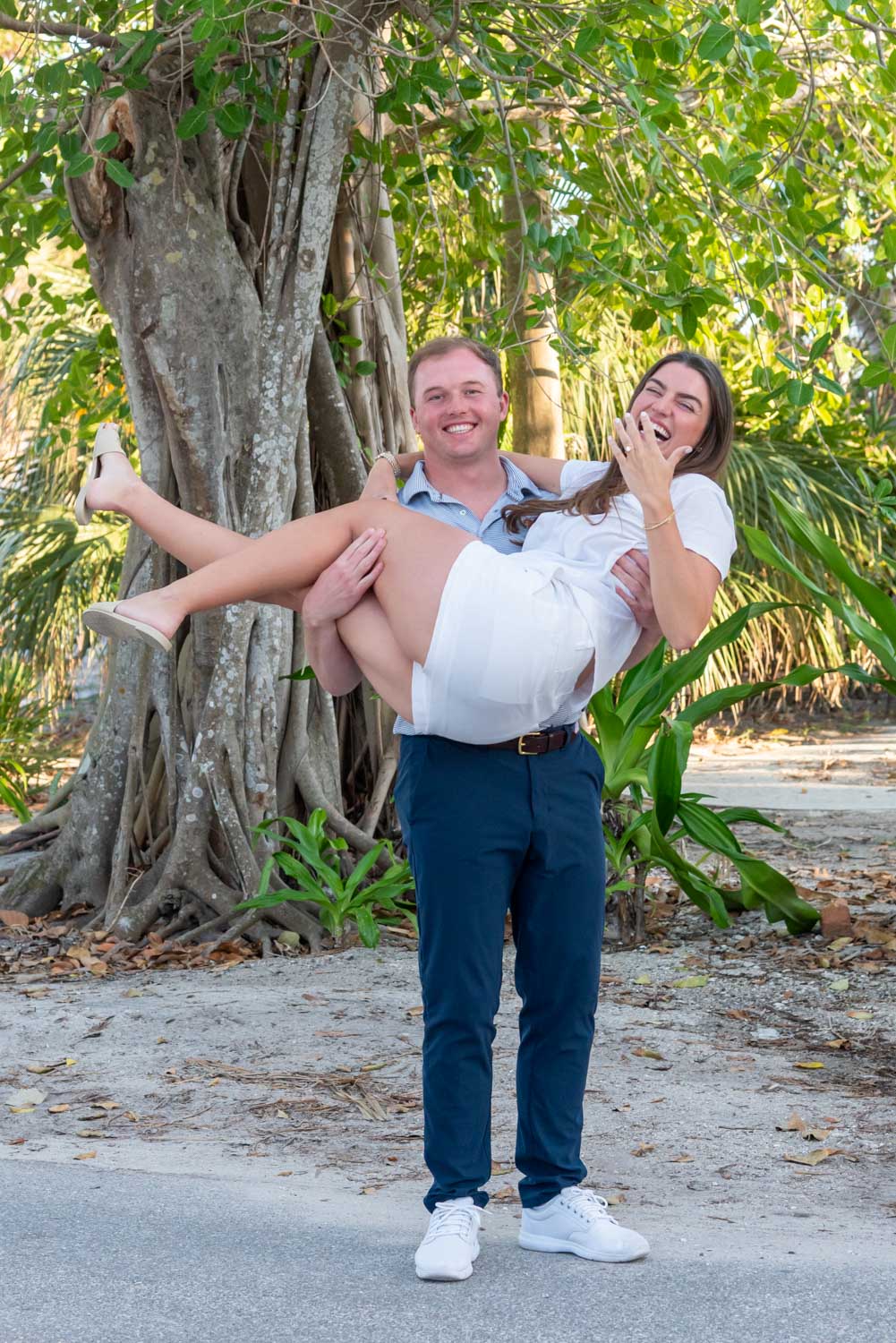 fiance lifts his girlfriend up after proposing to her on Banyan Street