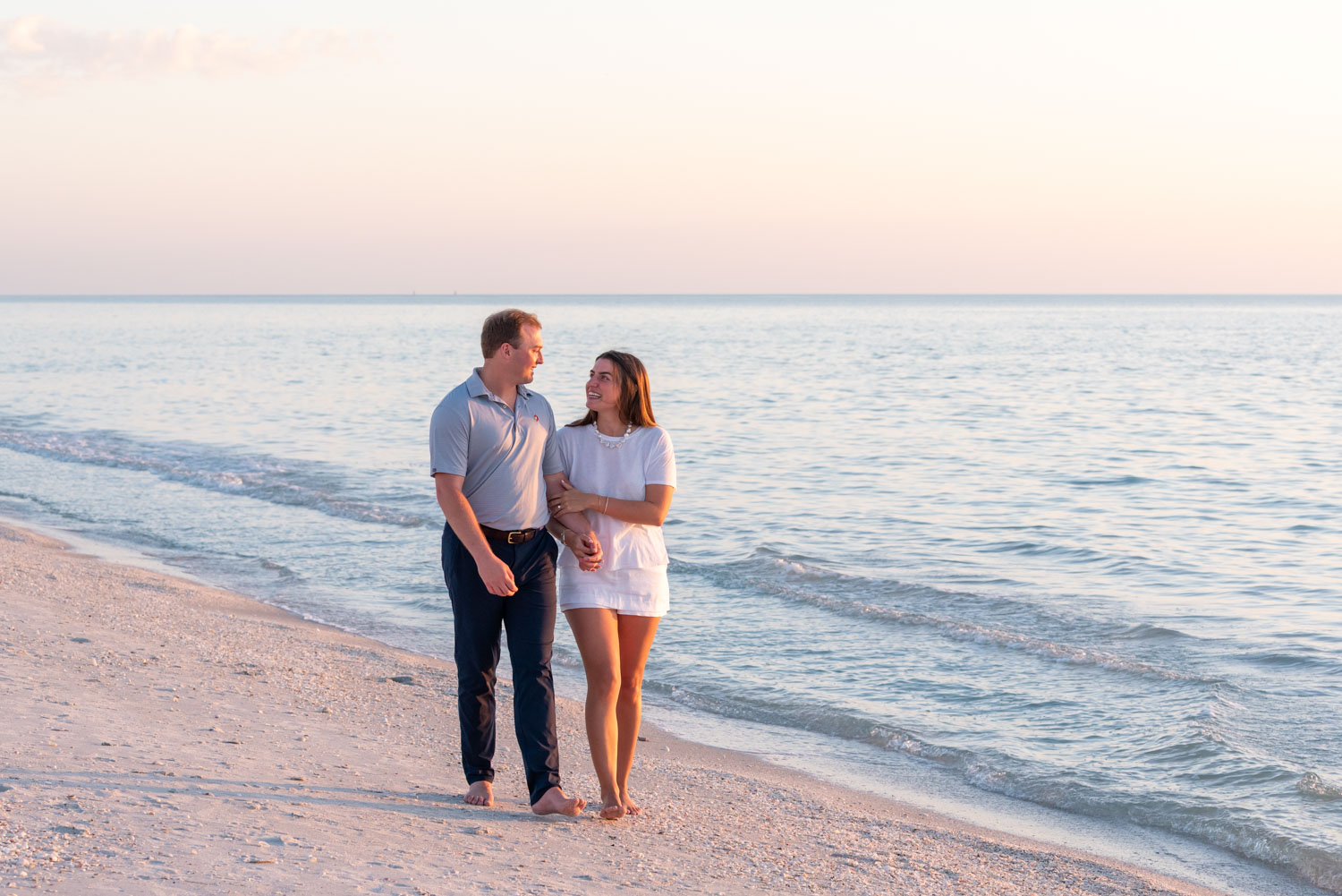 Boca Grande surprise engagement with couple walking along beach at sunset