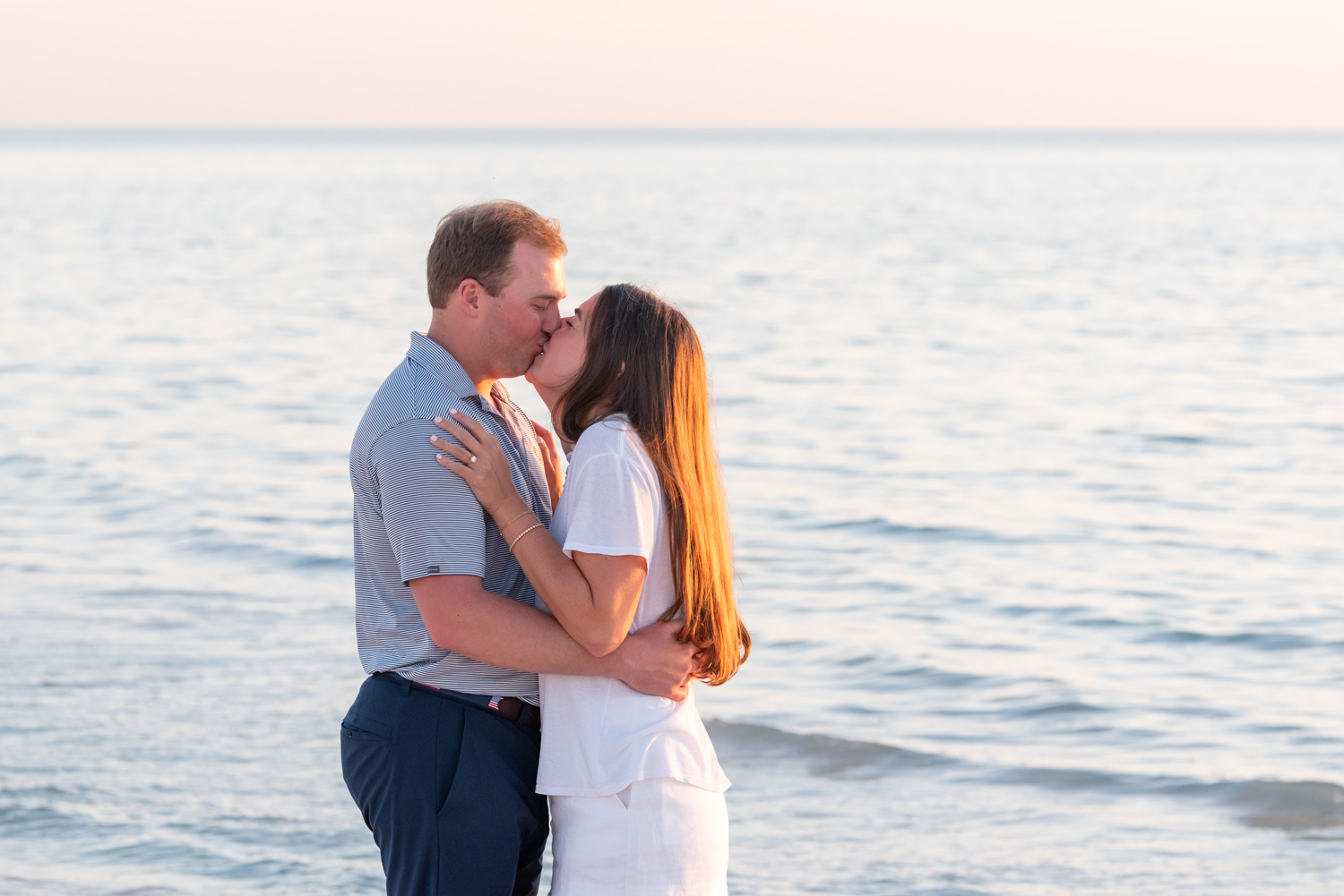 couple spontaneously kiss as they stand on the beach