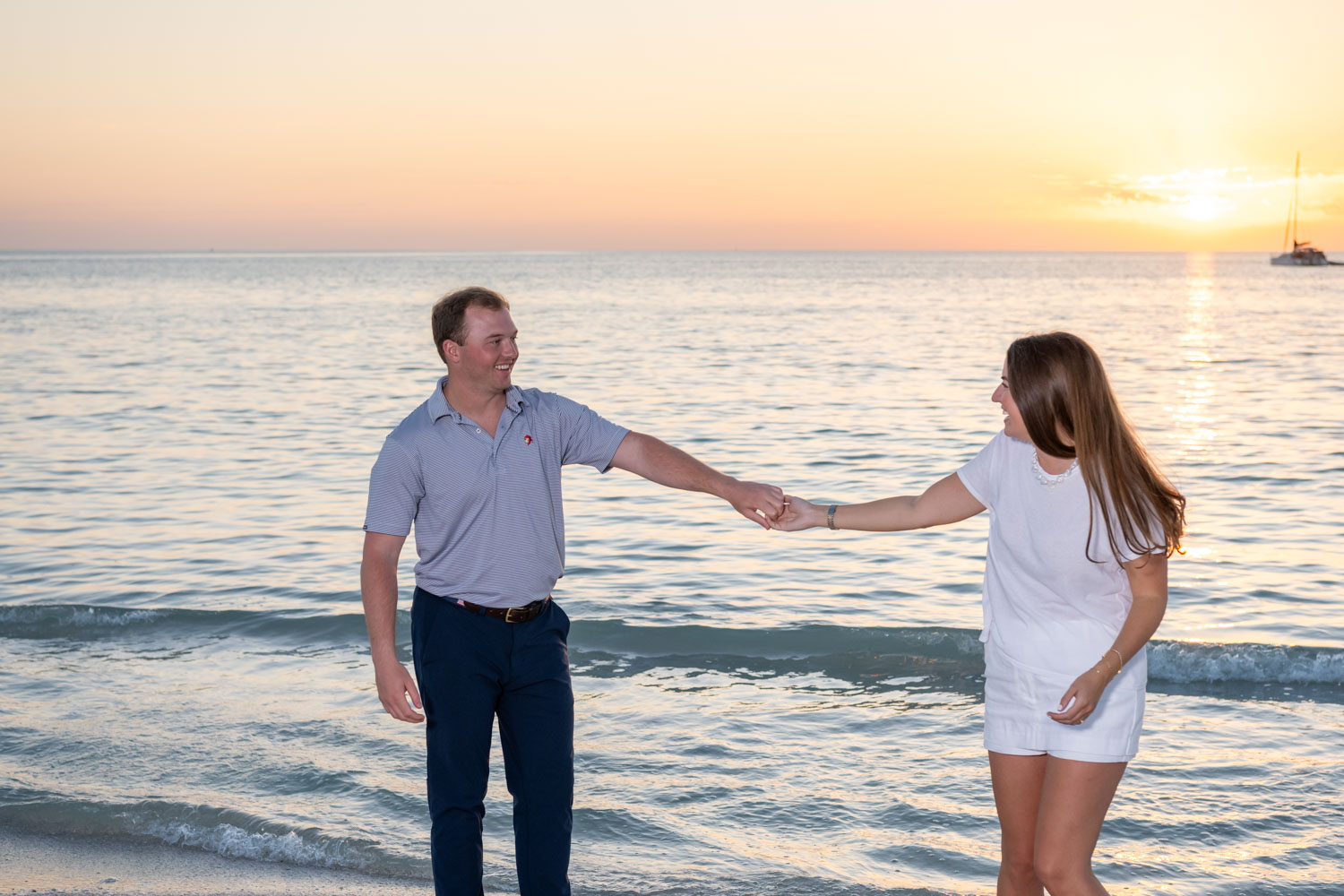newly engaged couple dance on the beach at sunset
