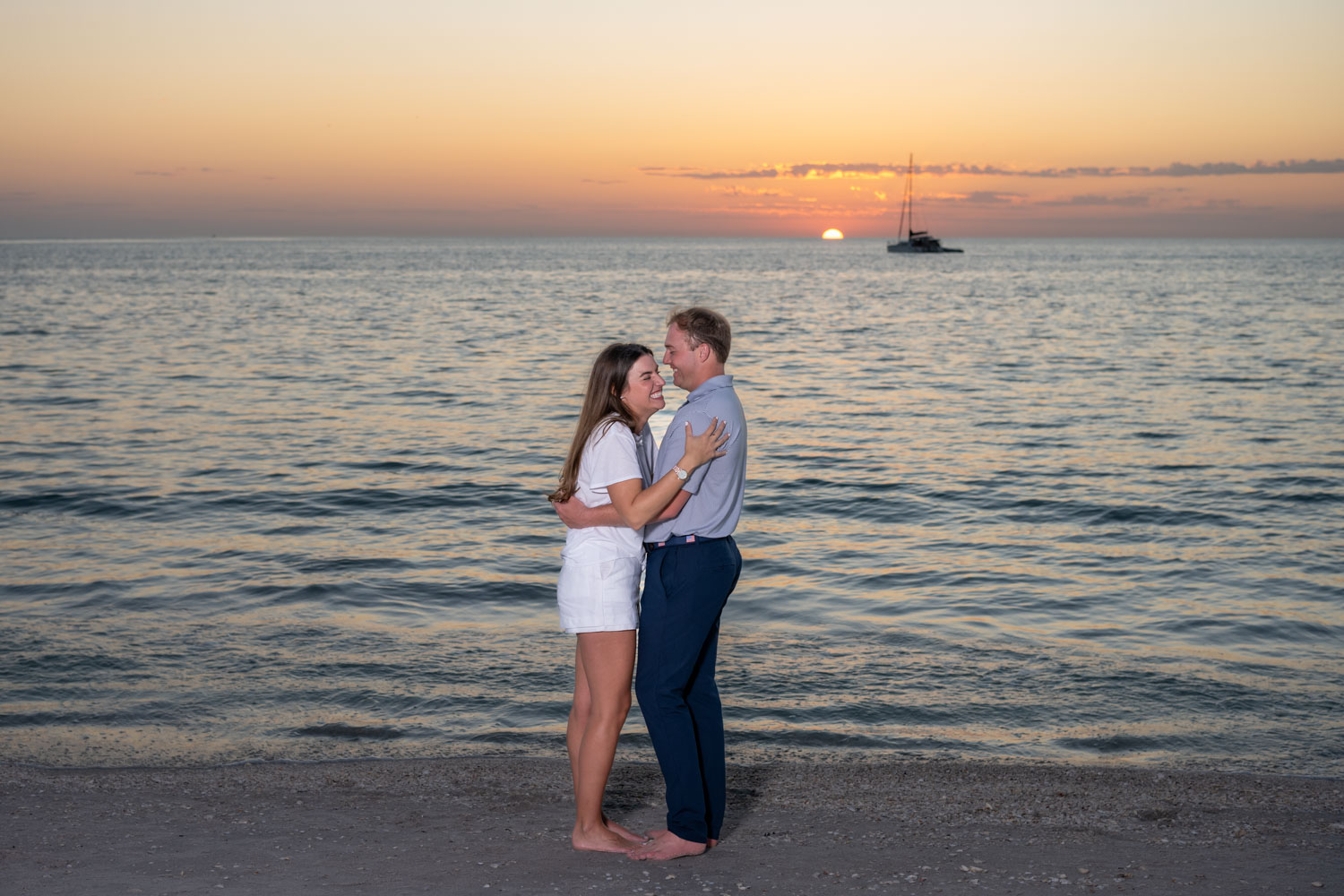 couple holding each other on the beach at sunset