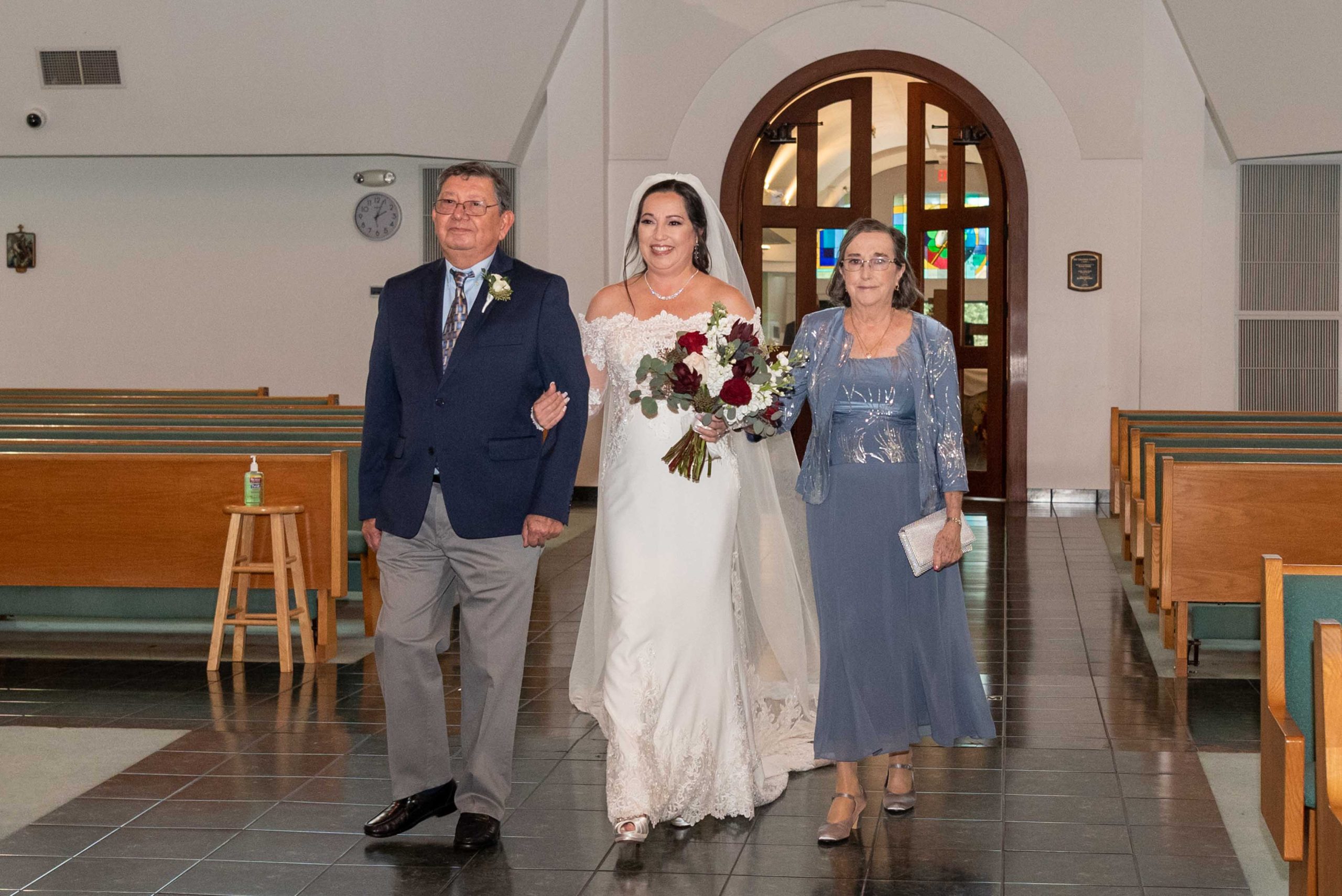 bride with her parents walking down the aisle