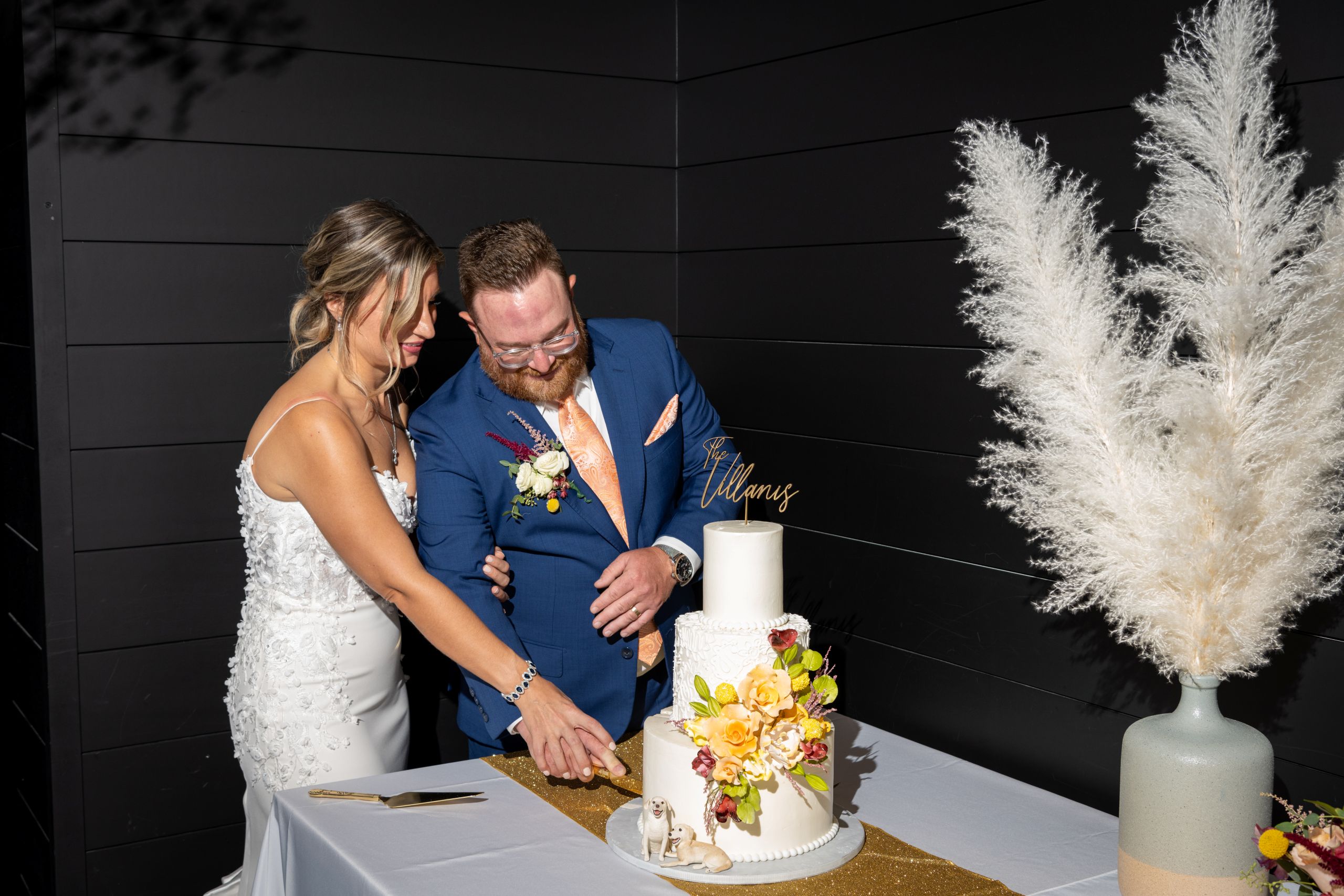 bride and groom with a knife cutting into their three tiered wedding cake