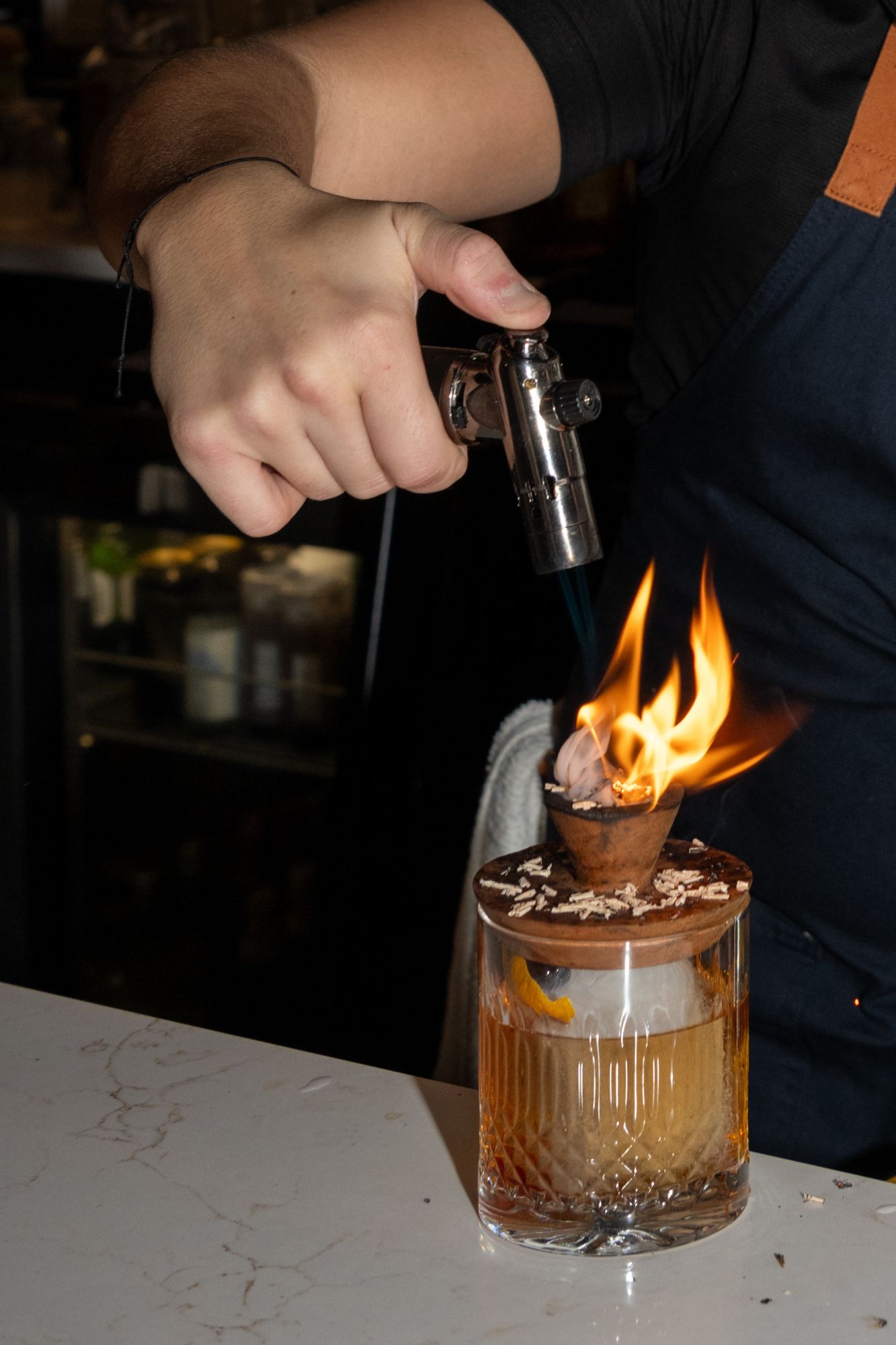 bartender lighting up a specialty cocktail