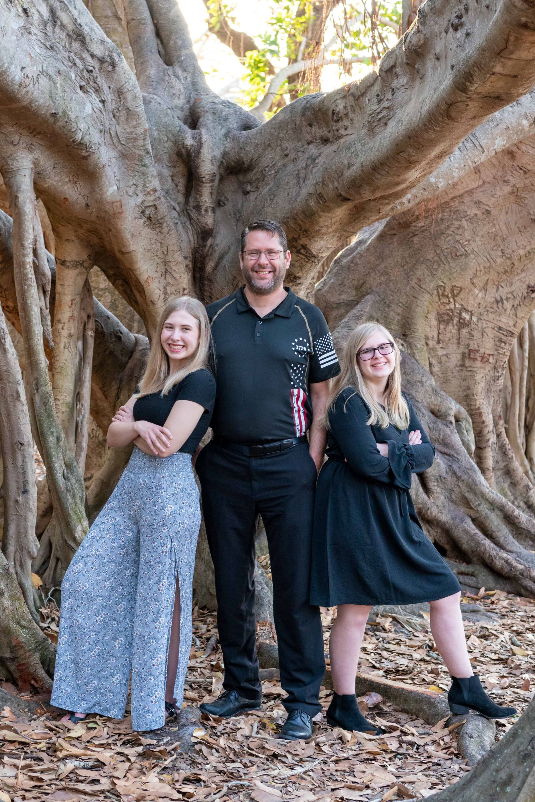 father with his two teenage daughters in front of a banyan tree