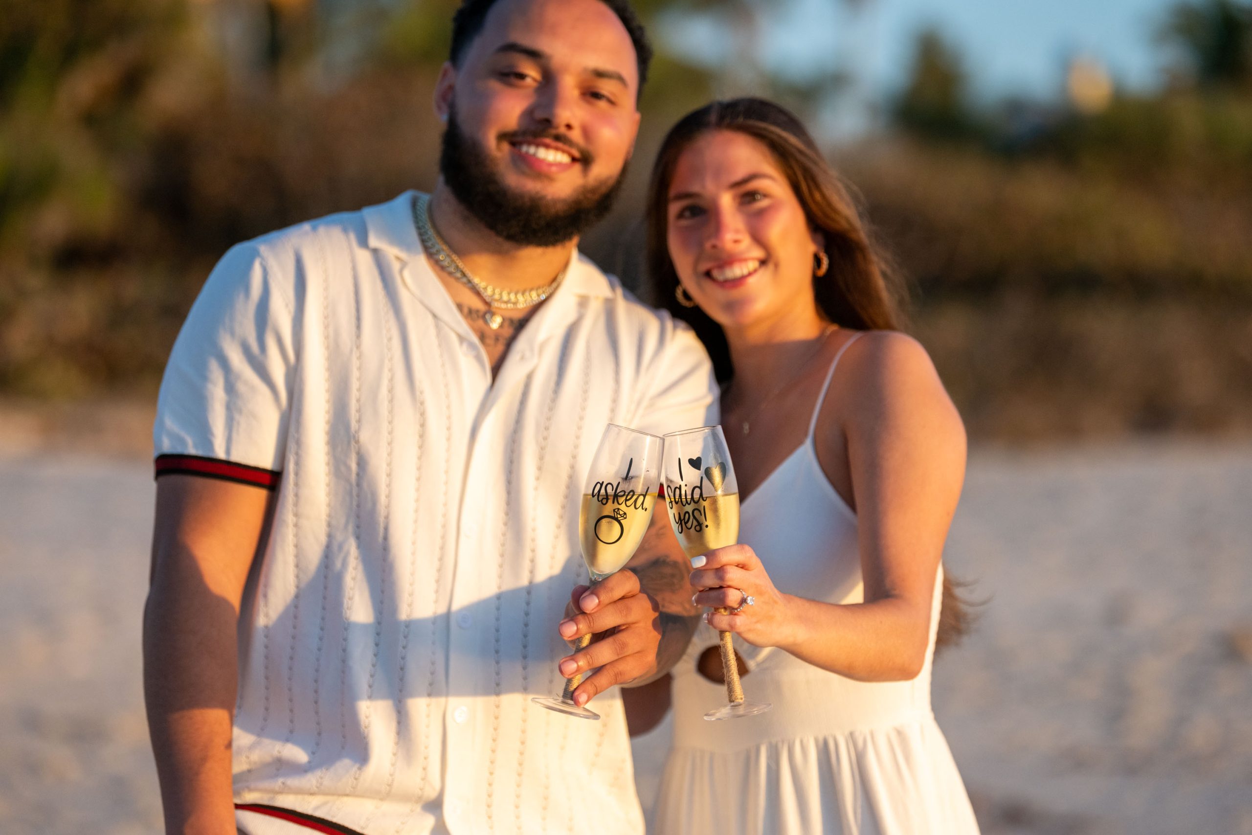newly engaged couple show off champagne glasses