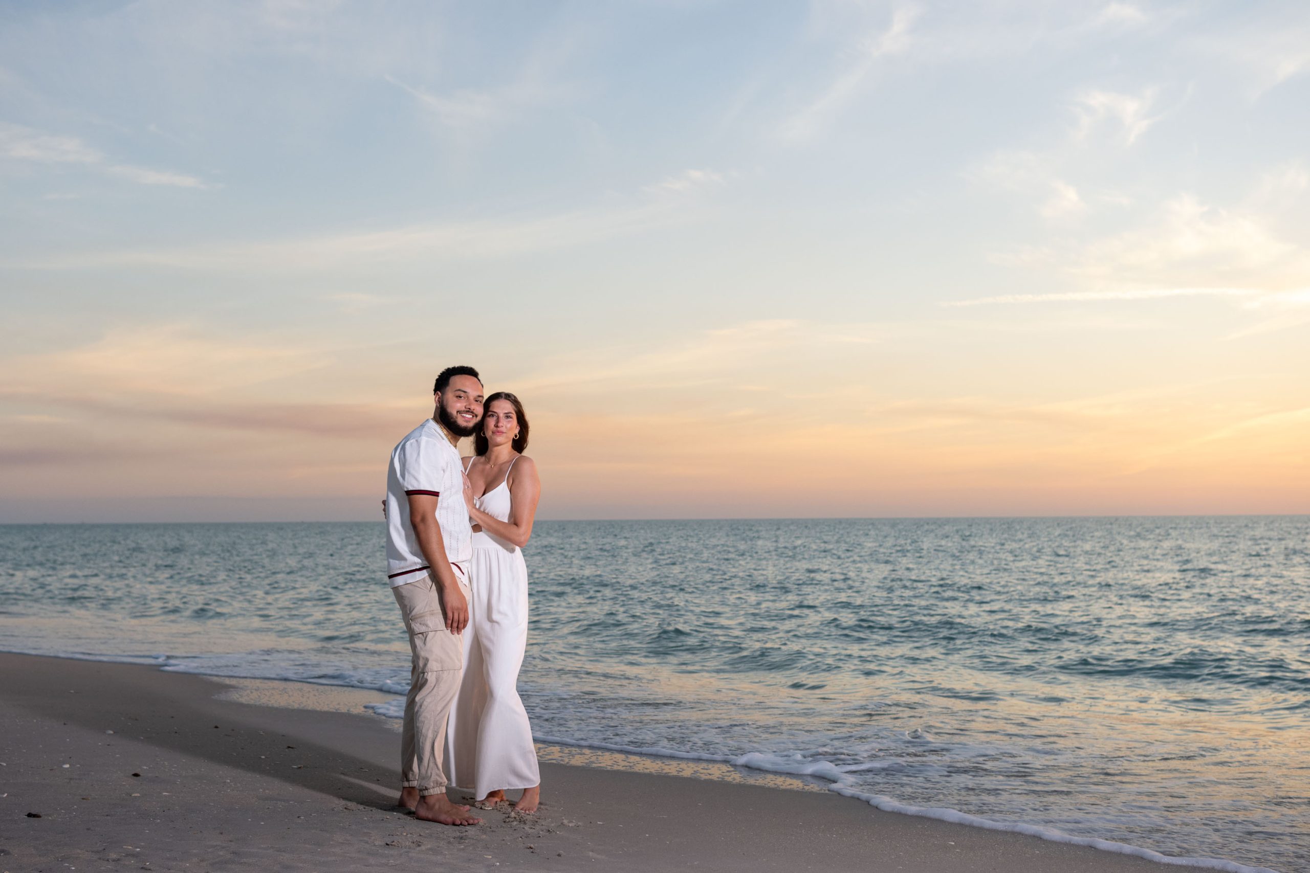 newly engaged couple embrace on Casey Key beach at sunset