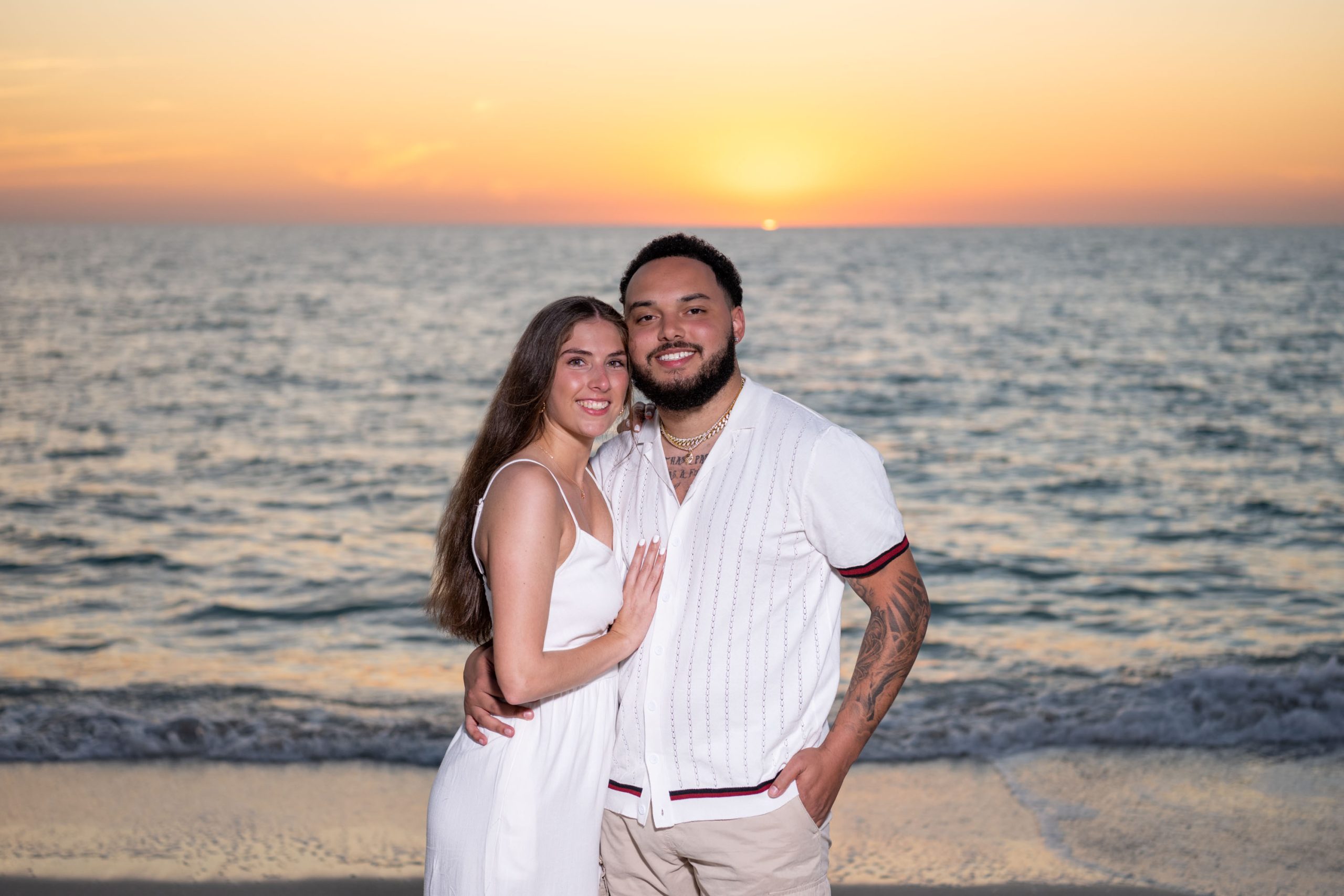 engaged couple smile together as the sun sets over the Gulf