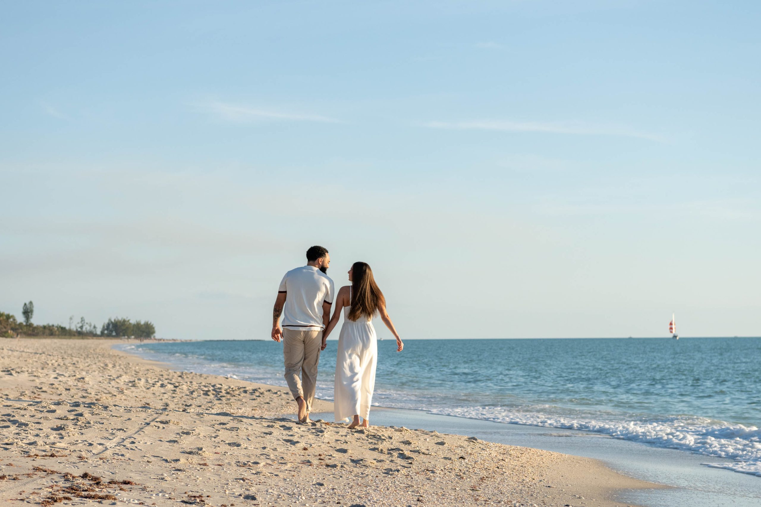 engaged couple walk down the beach, talking quietly to each other