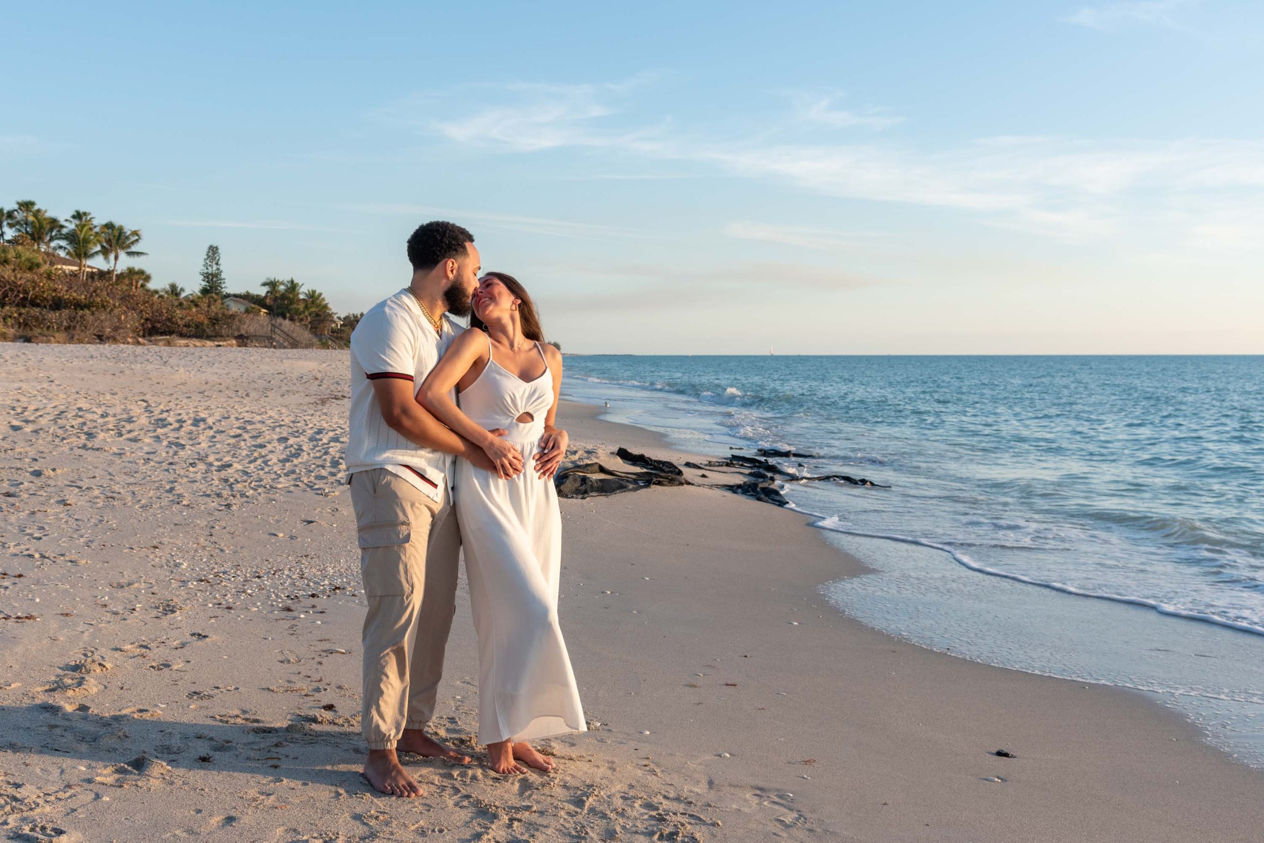 newly engaged couple embrace on the beach