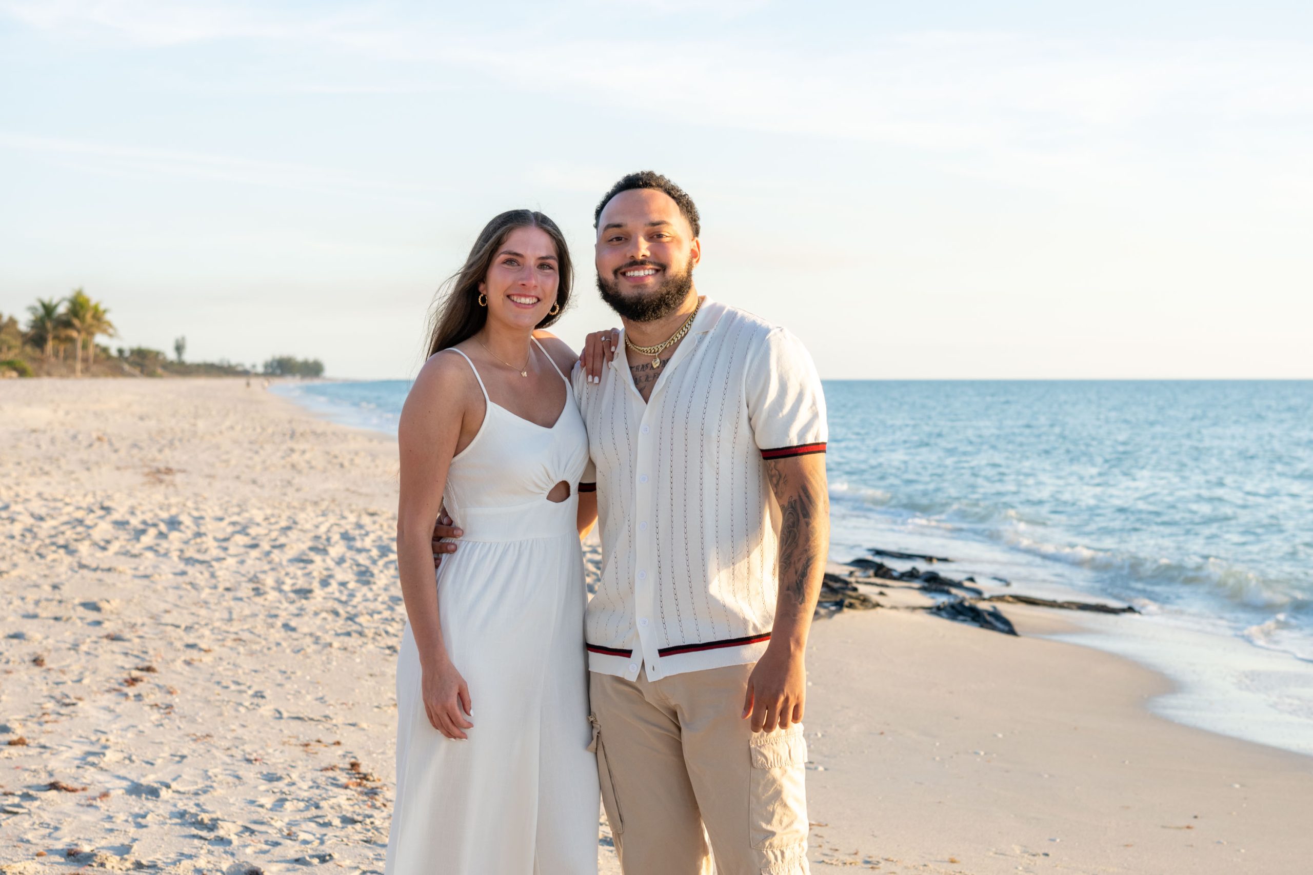 newly engaged couple stand together on Casey Key beach smiling