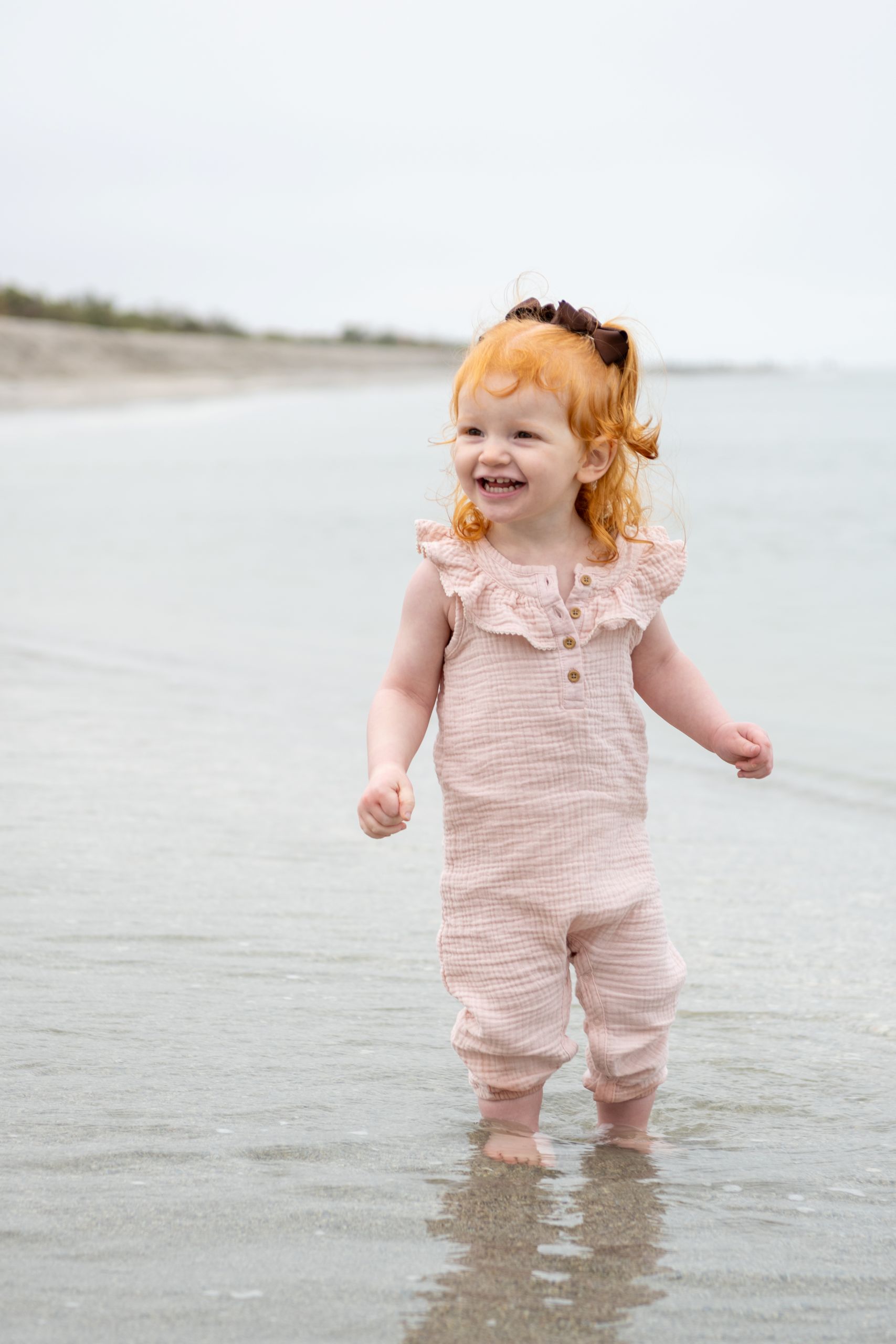 little girl smiles as she wades into the water
