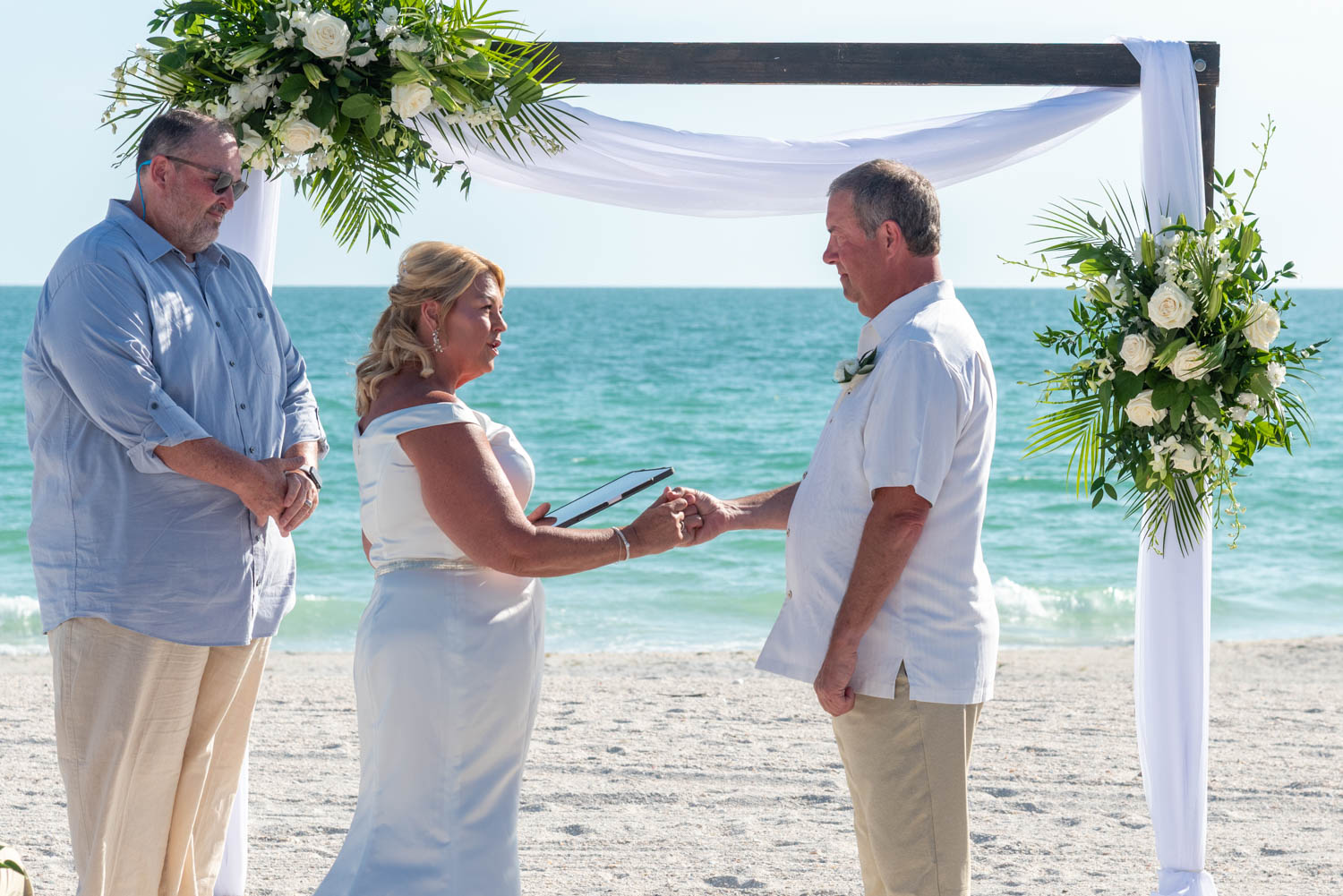 bride and groom holding hands to connect during their wedding ceremony at Lido Beach Resort