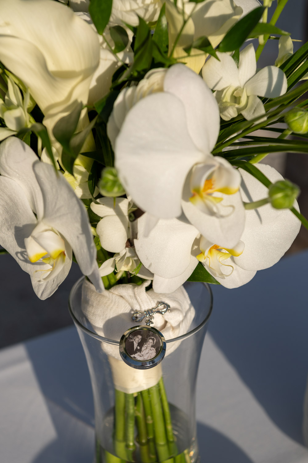 white wedding flowers in a vase with family locket attached