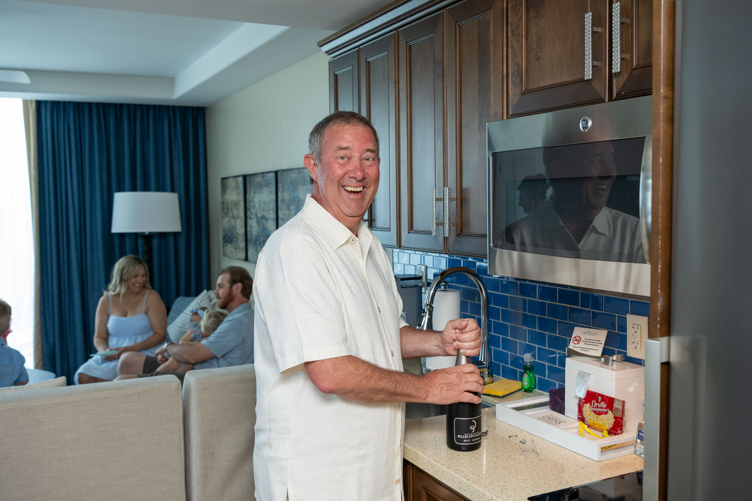 groom happily uncorking a bottle of champagne