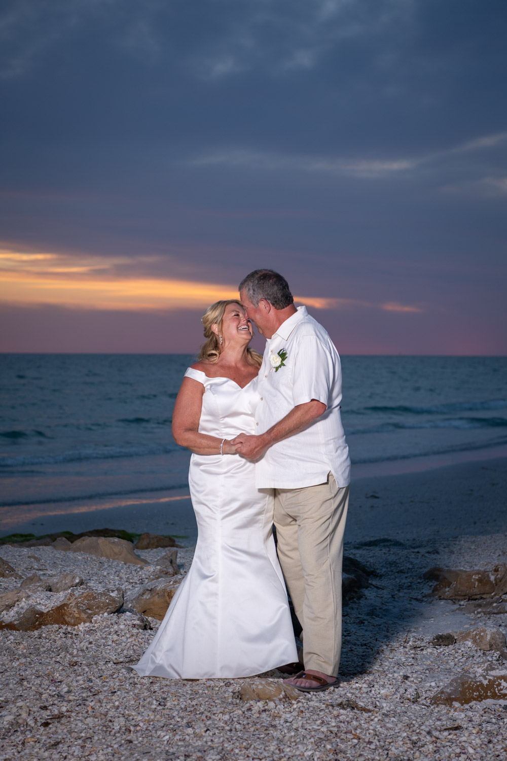 bride and groom look at each other and smile as the sky turns purple from sunset after wedding on Lido Key