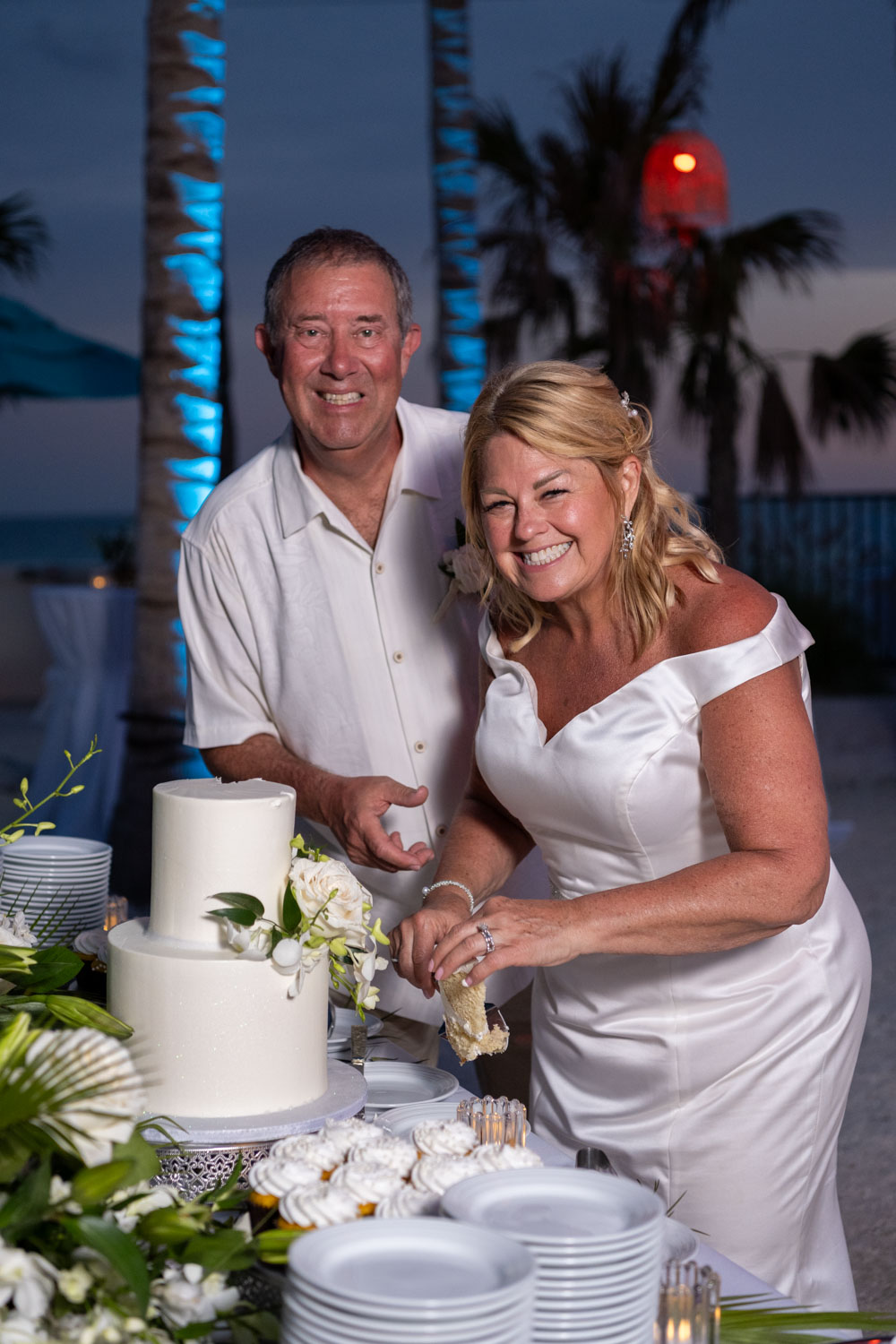 bride and groom smile as they get ready to cut their wedding cake