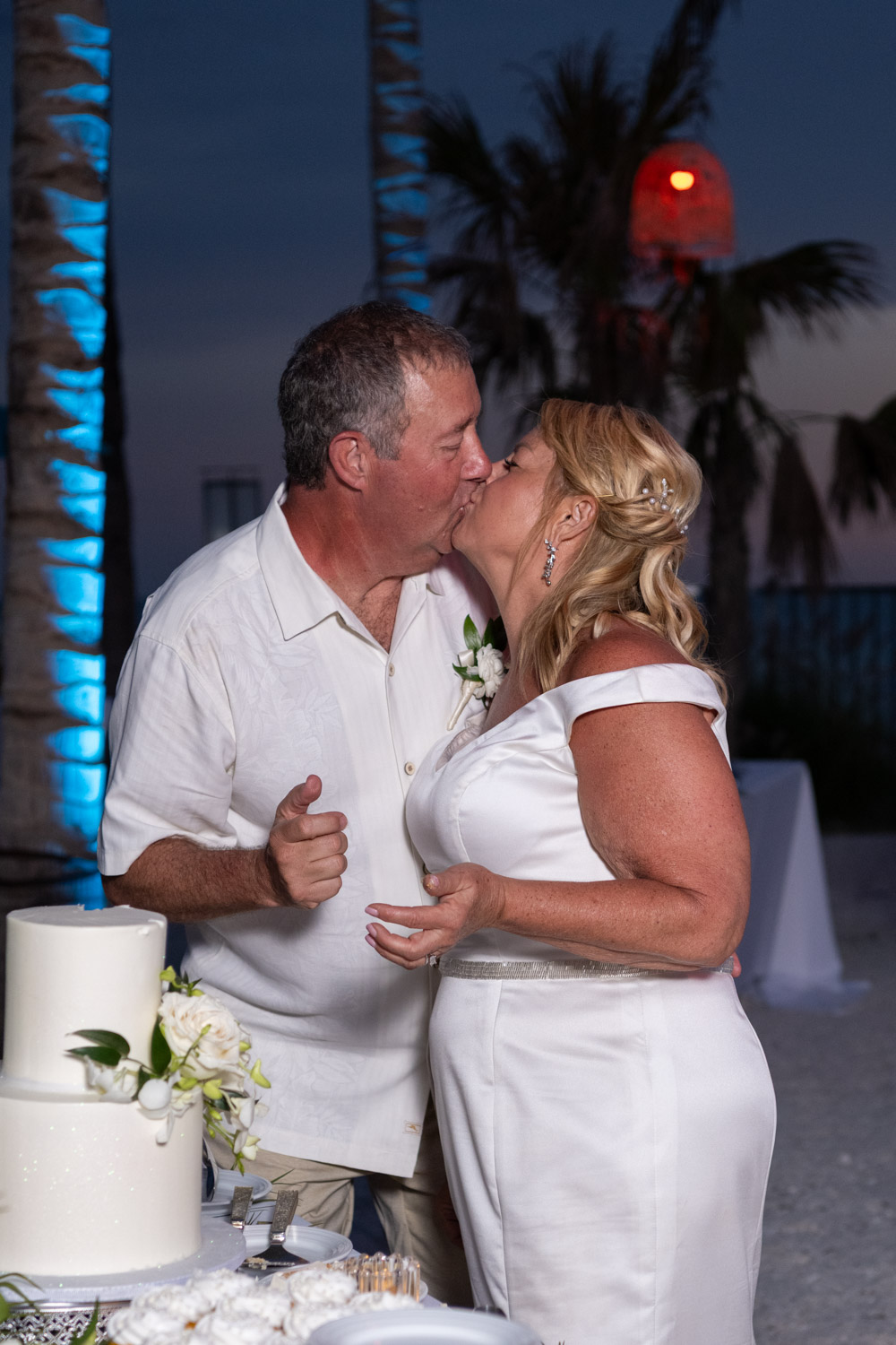 bride and groom kiss after sharing wedding cake