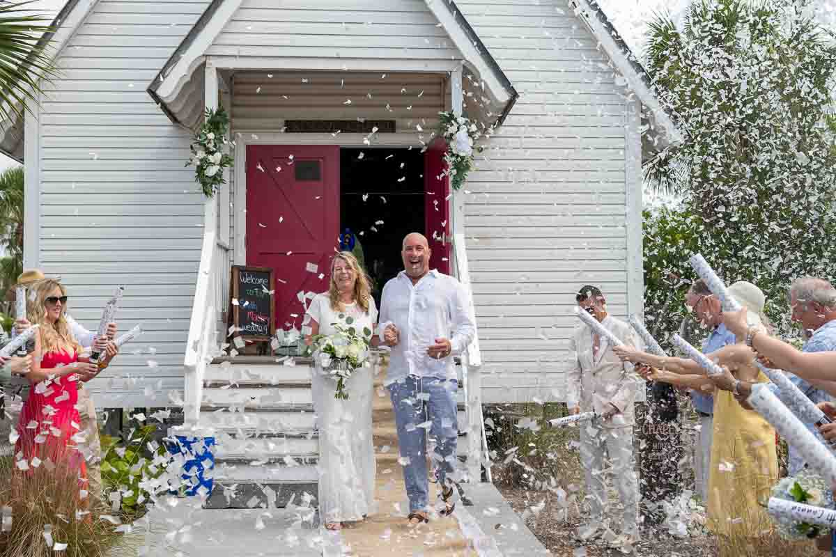 bride and groom exit church while guests shower them with confetti