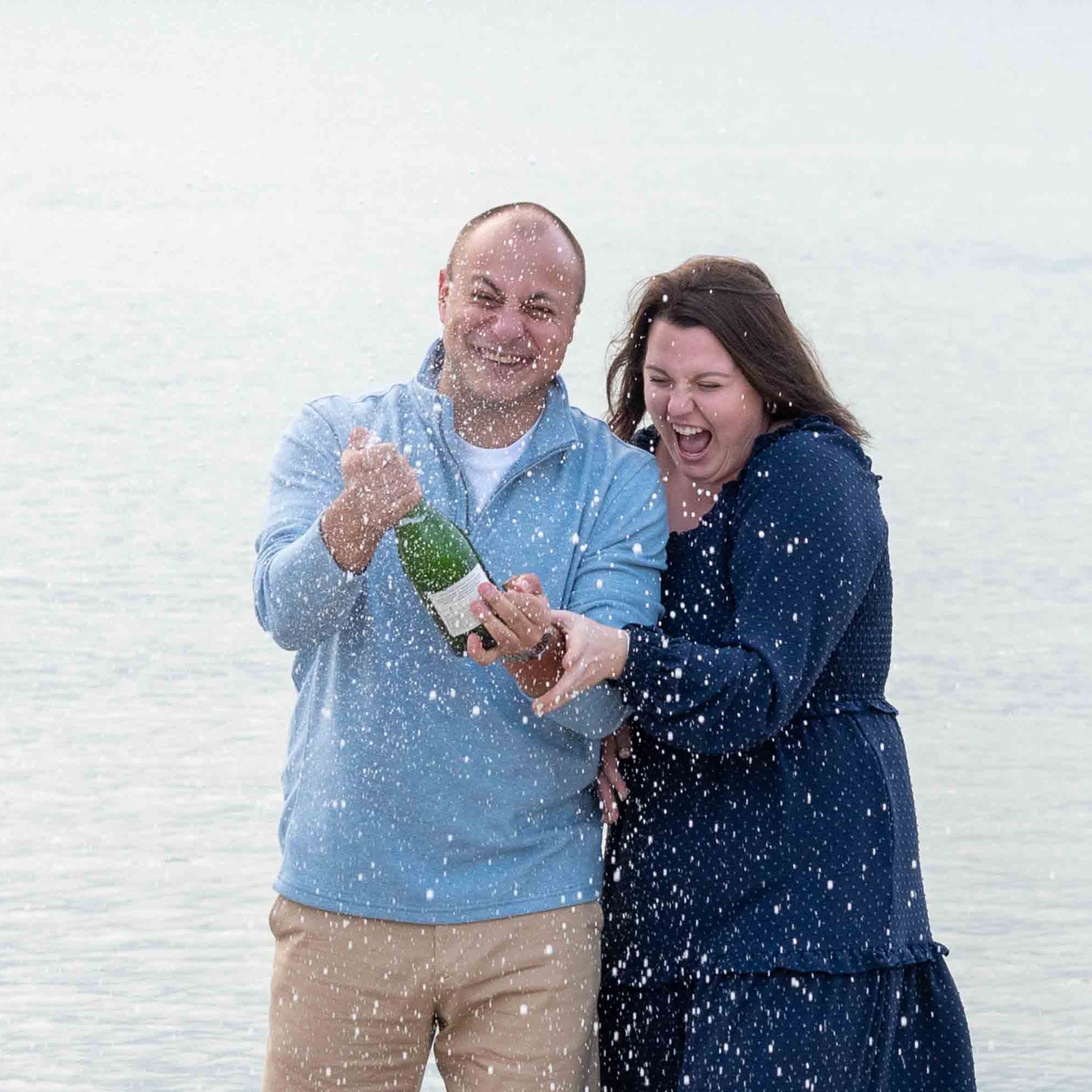 couple pops open a bottle of champagne